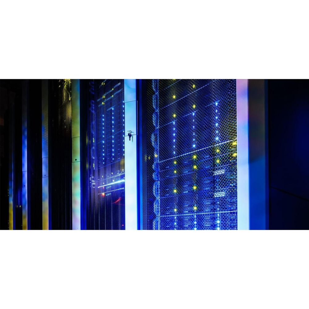 Regały serwerowe z niebieskimi i żółtymi światłami w ciemnym pomieszczeniu.