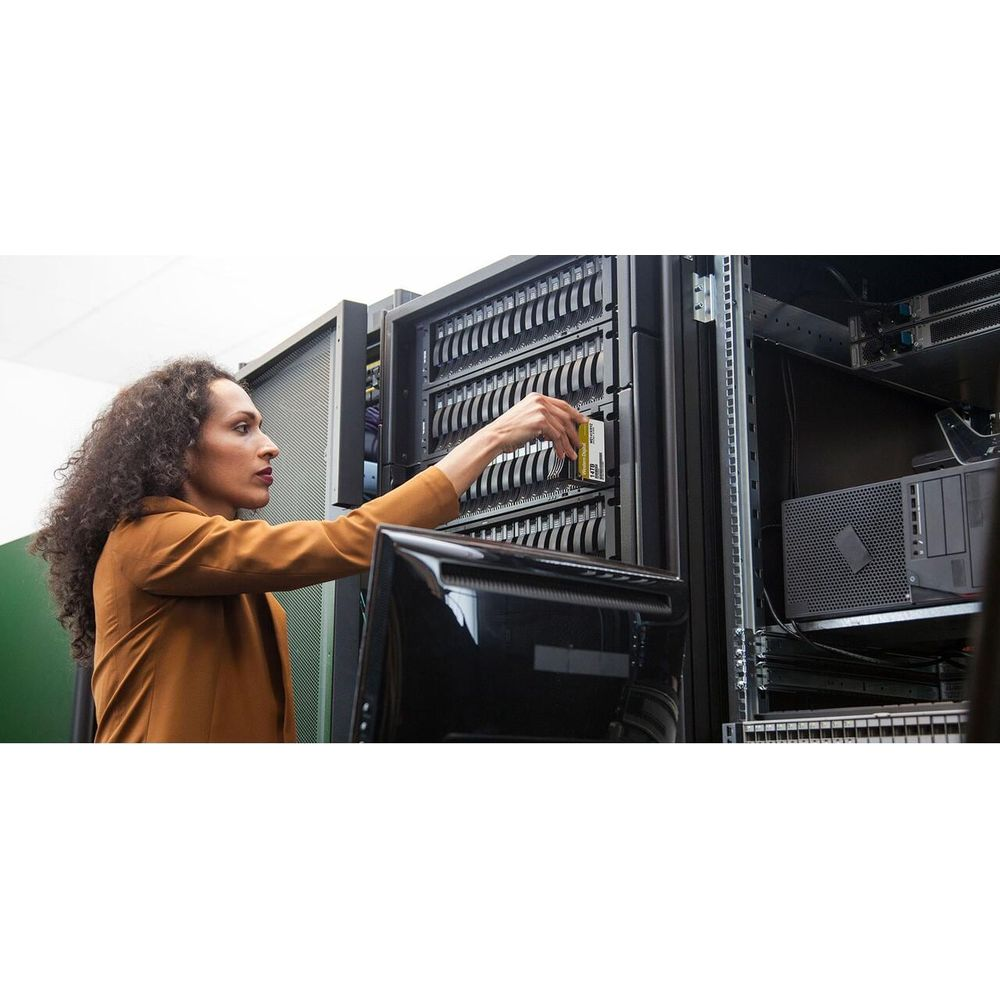 Kobieta z kręconymi włosami wkłada dysk twardy do szafy serwerowej.