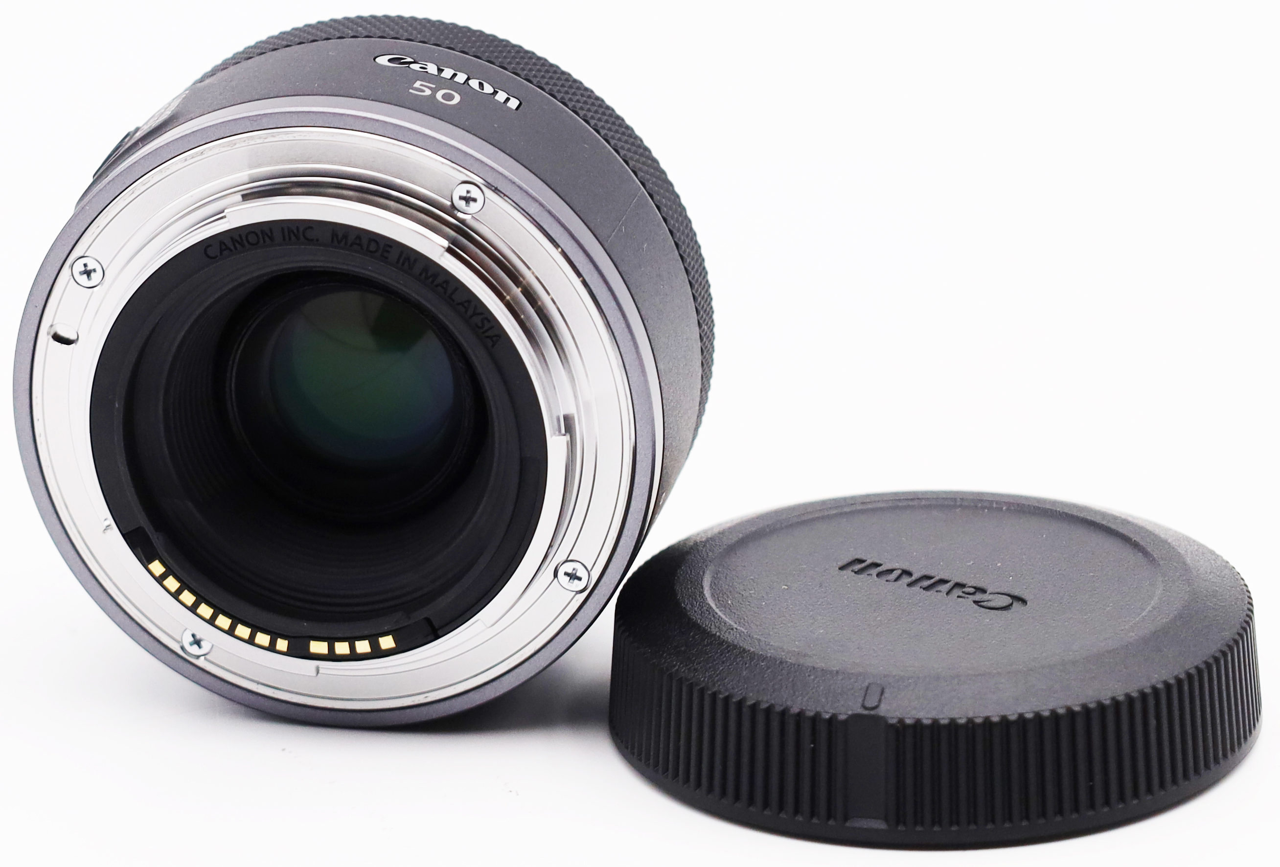 Primer plano de la parte trasera de un objetivo Canon 50mm, con su tapa al lado.