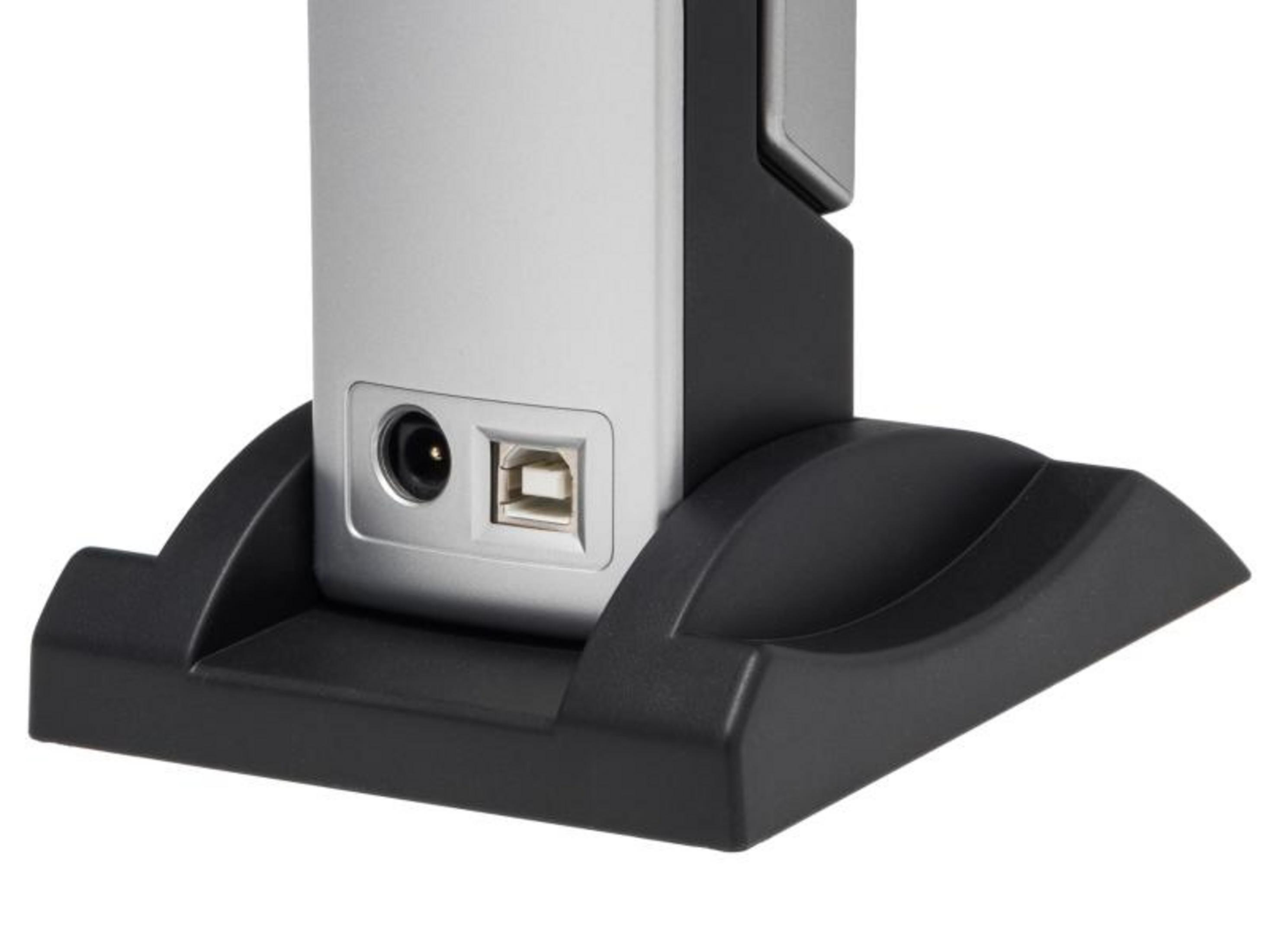 Silbernes Gerät mit USB- und Stromanschluss auf schwarzem Sockel.