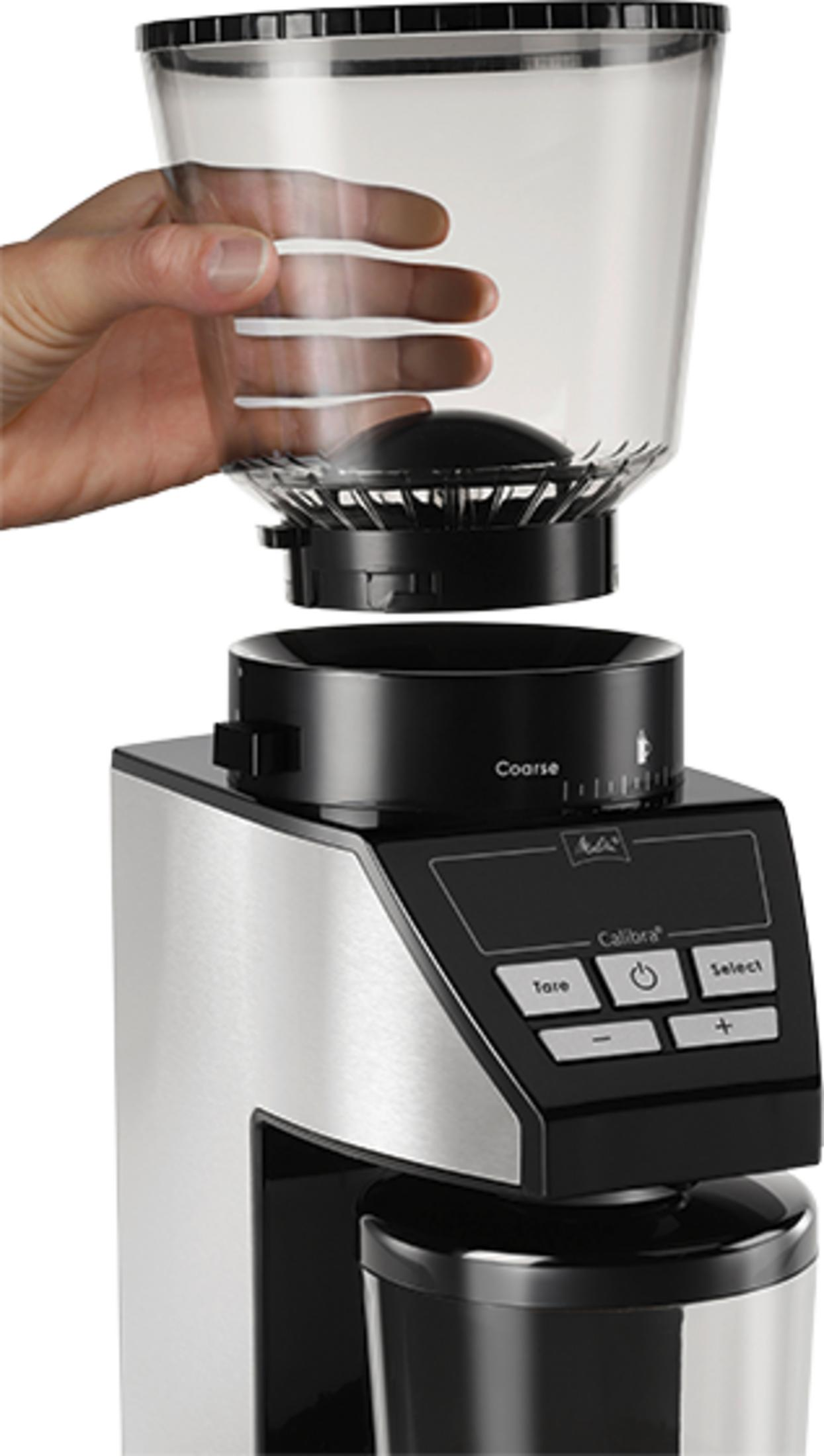 Eine Hand hält den oberen Behälter eines Kaffeemühle, die mit Edelstahldetails.