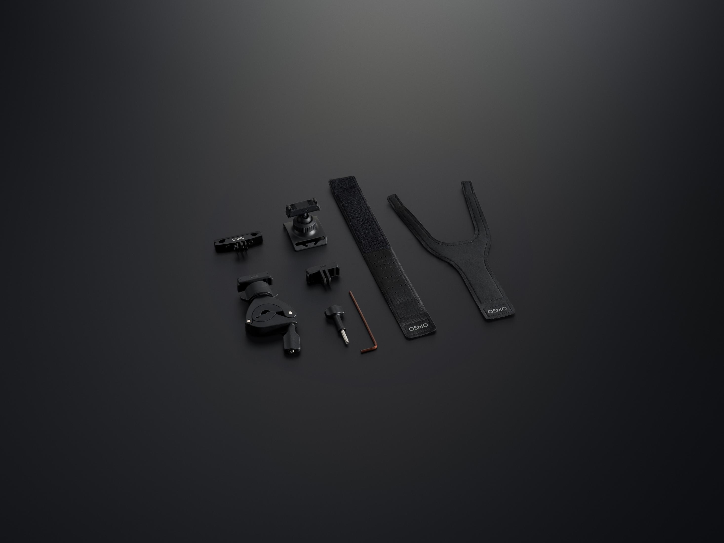 Accesorios negros y grises: pinza, soporte, correa y herramienta sobre fondo oscuro.