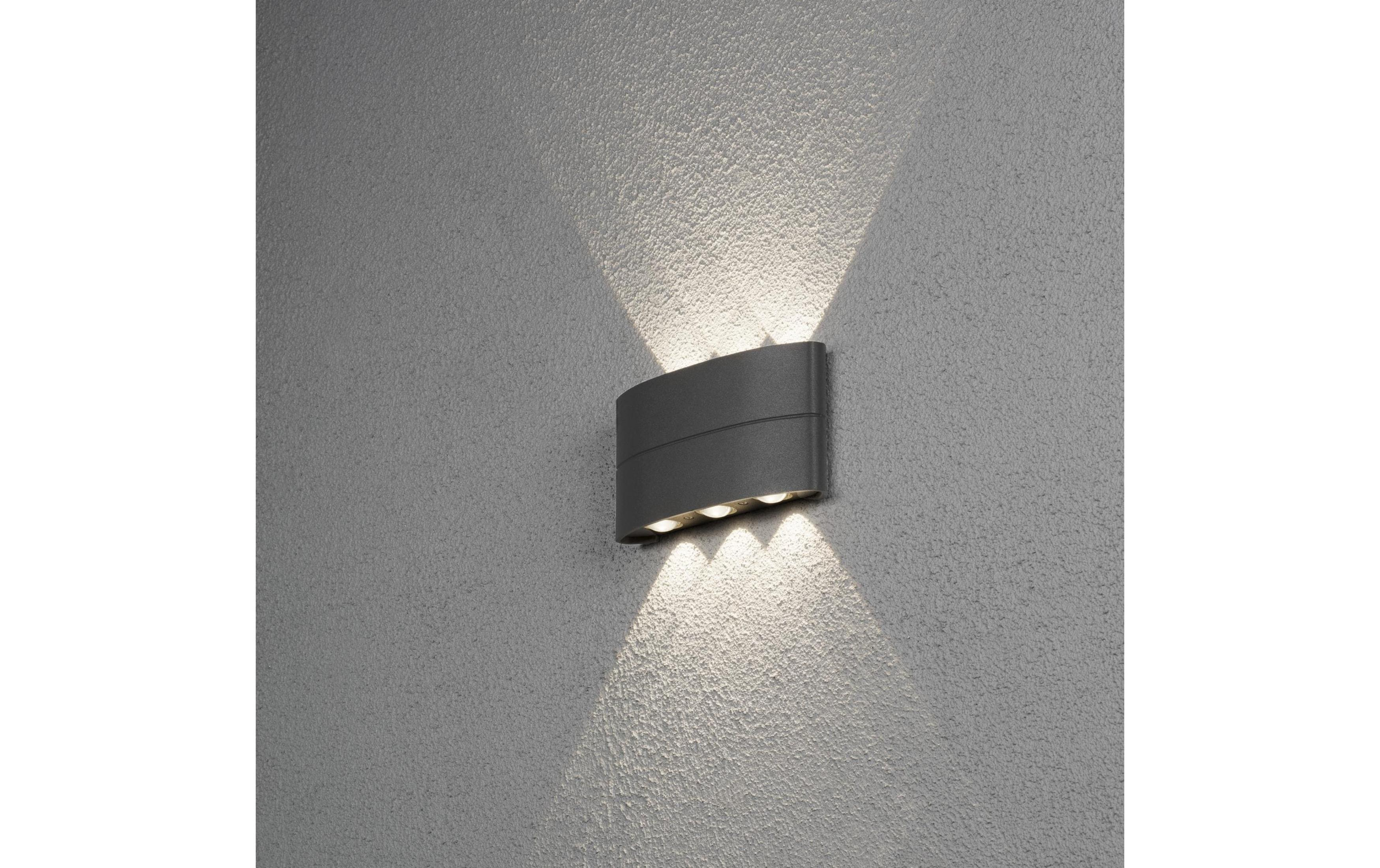 Applique da parete grigia illumina parete testurizzata con due fasci di luce.