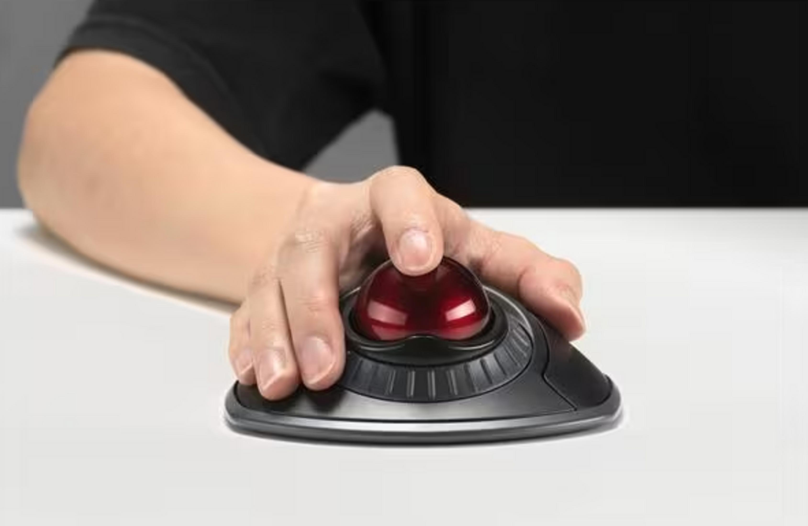 Mano che utilizza un mouse trackball nero con sfera rossa su una scrivania bianca.