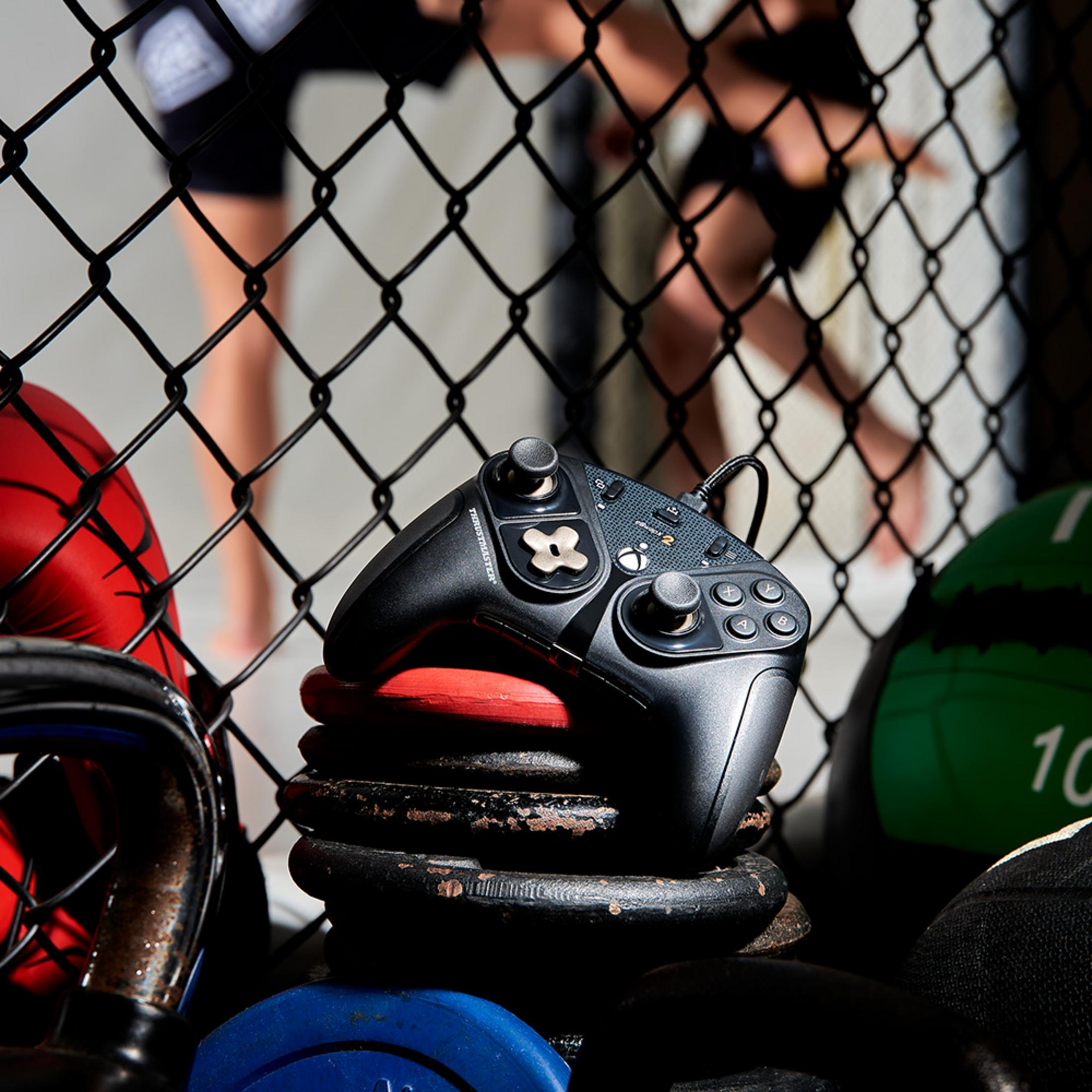 Czarny kontroler spoczywa na ciężarach w siłowni.