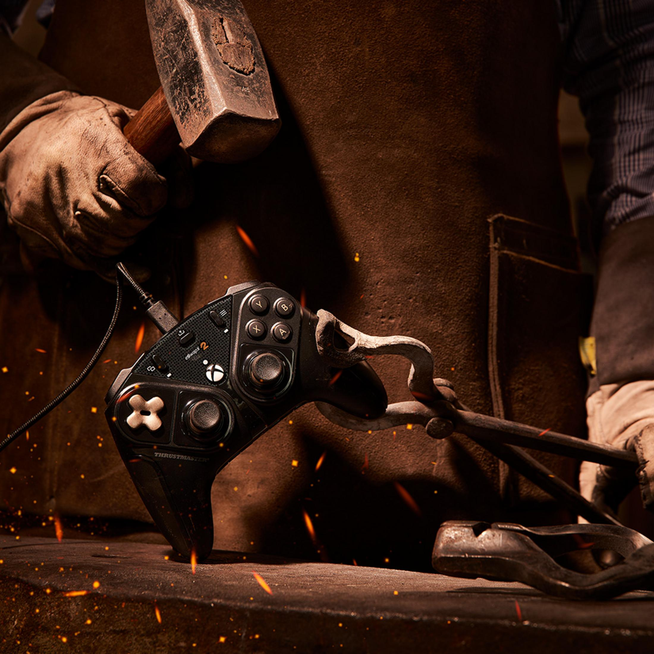 Osoba w skórzanym fartuchu trzyma kontroler z młotkiem i szczypcami.