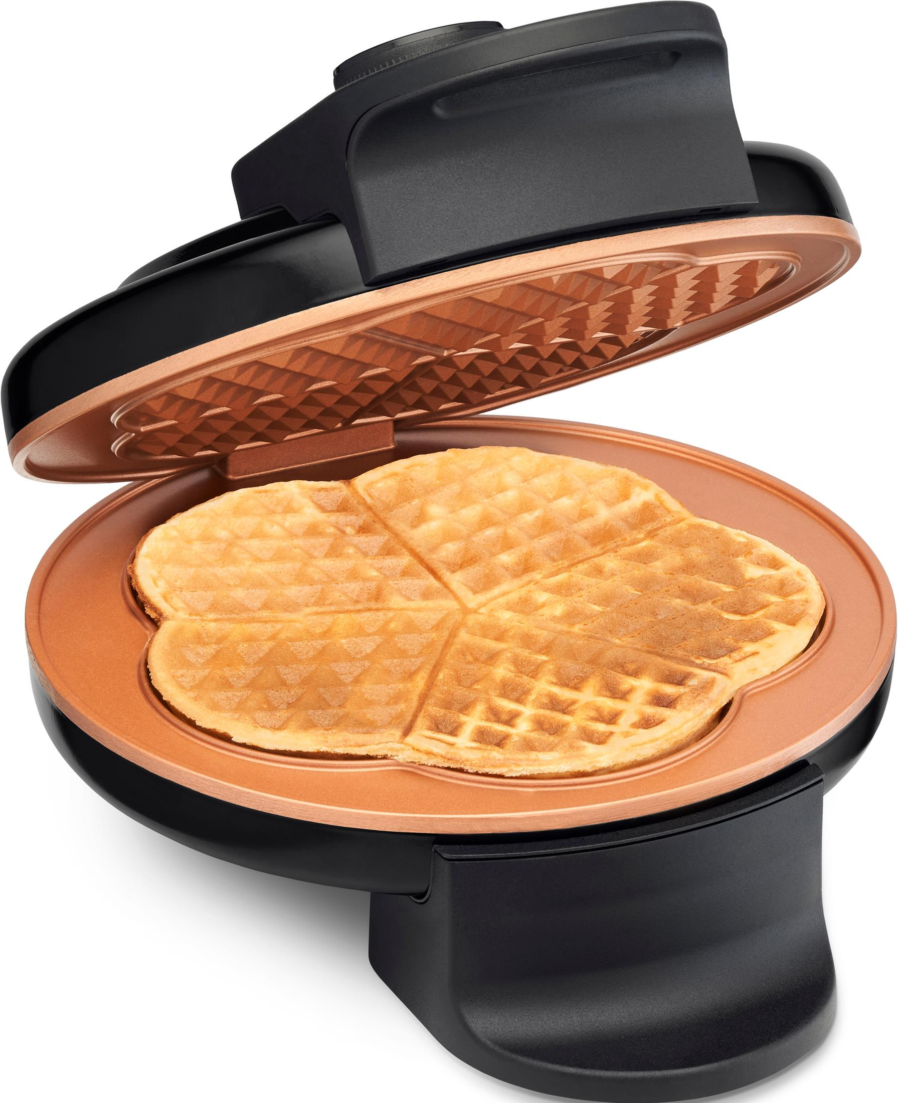 Ein offener Waffelautomat mit einem goldbraunen Herz-Waffel darin.