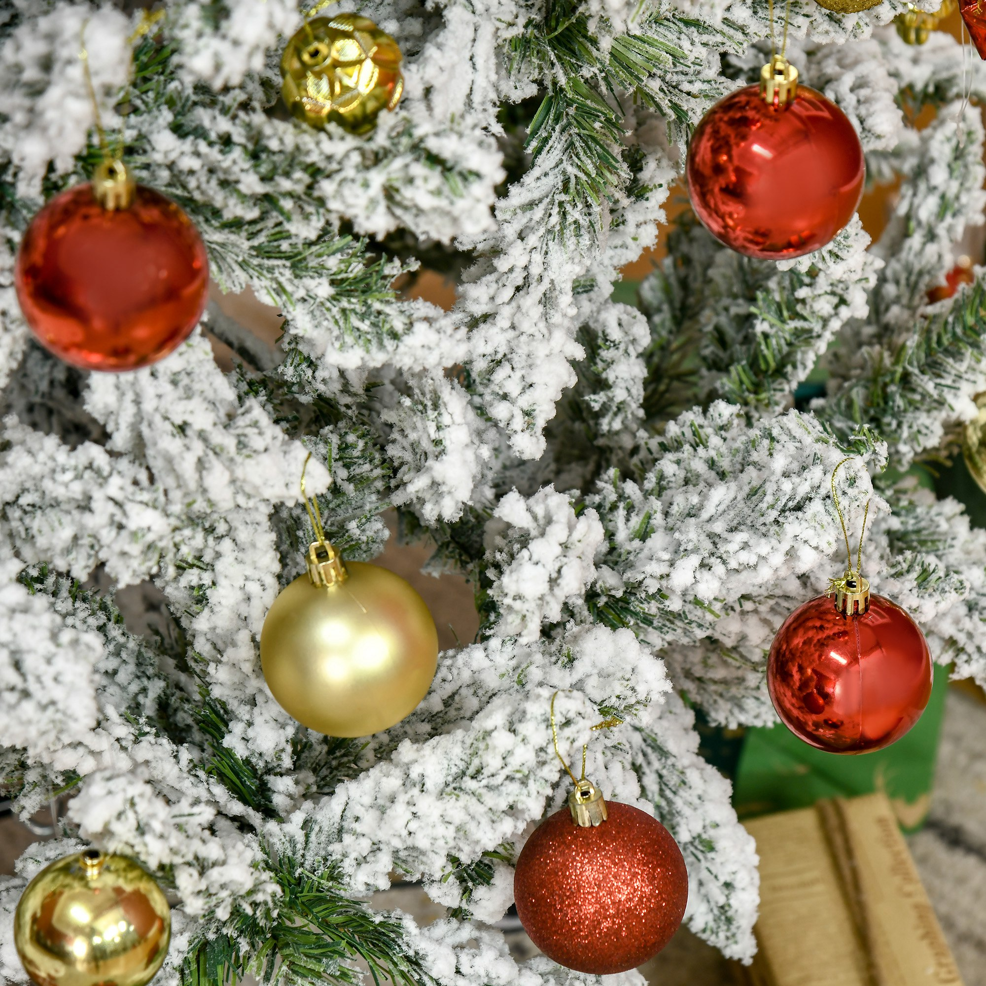 Un árbol de Navidad nevado con adornos rojos y dorados.