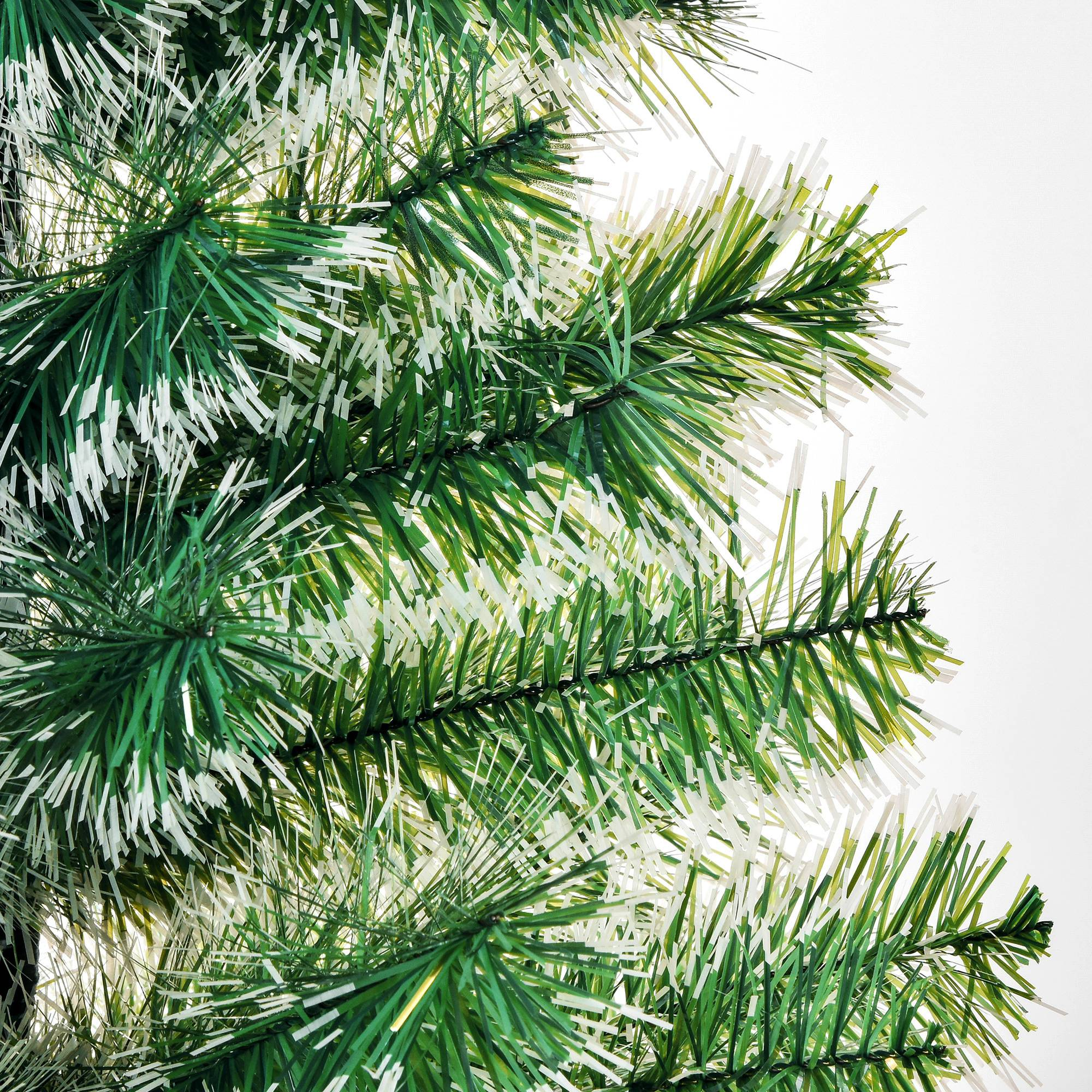 Primer plano de agujas de pino verdes y blancas en un árbol de Navidad artificial.