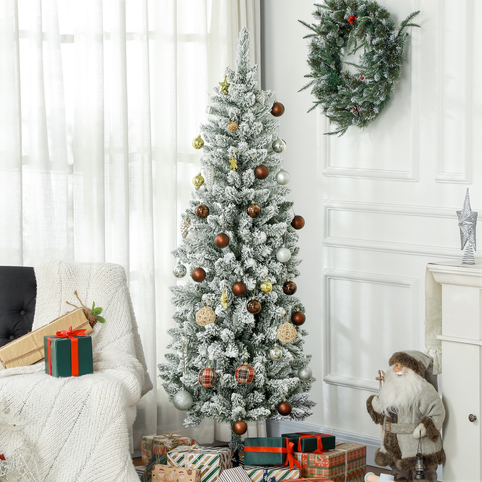 Un árbol de Navidad cubierto de nieve con adornos marrones y plateados, regalos y figura de Papá Noel.