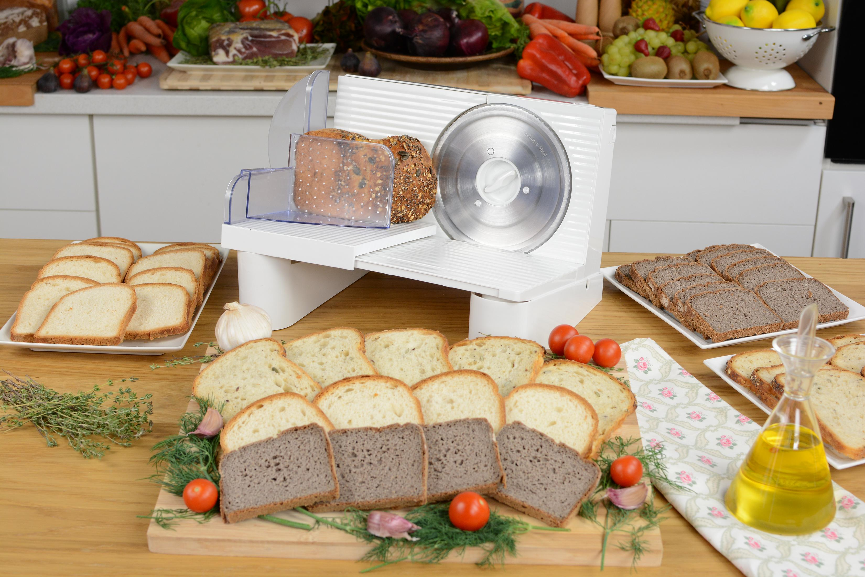 Affettatrice elettrica per pane con pane e verdure su un tavolo di legno.