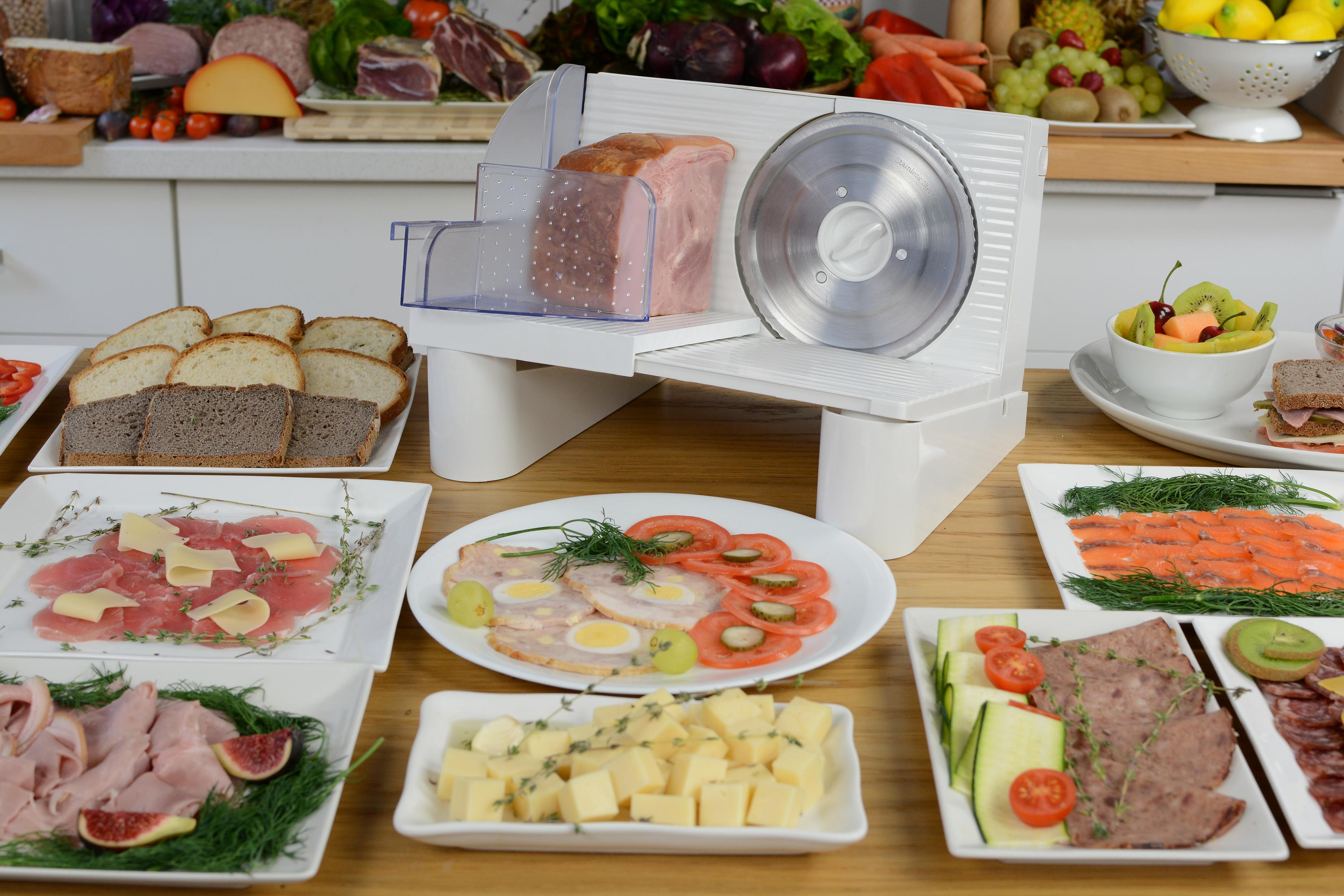 Affettatrice di carne con prosciutto, pane, salmone, formaggio e frutta.