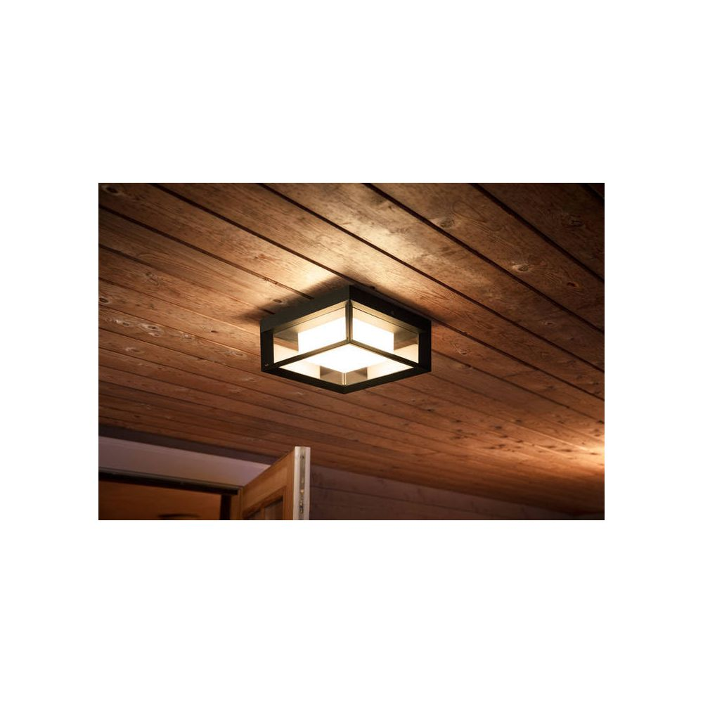 Nowoczesna lampa sufitowa z czarną ramą i białymi światłami na drewnianym suficie.