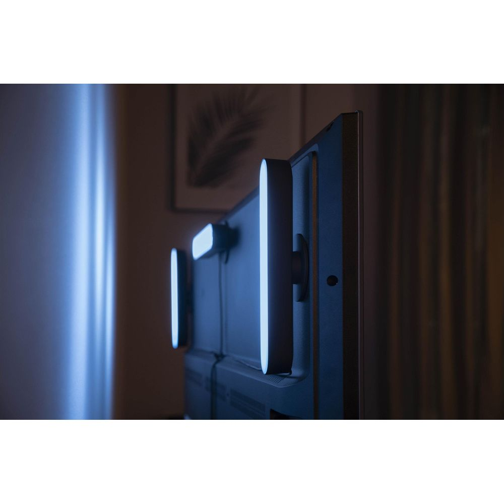 Une télévision avec deux barres lumineuses LED verticales à l'arrière dans une pièce sombre.
