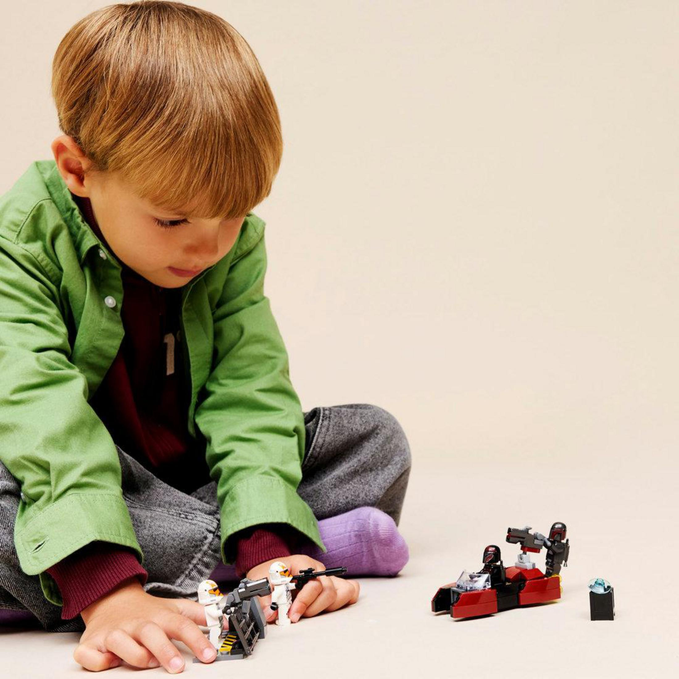 Un niño juega con figuras y vehículos de Lego de Star Wars sobre fondo claro.