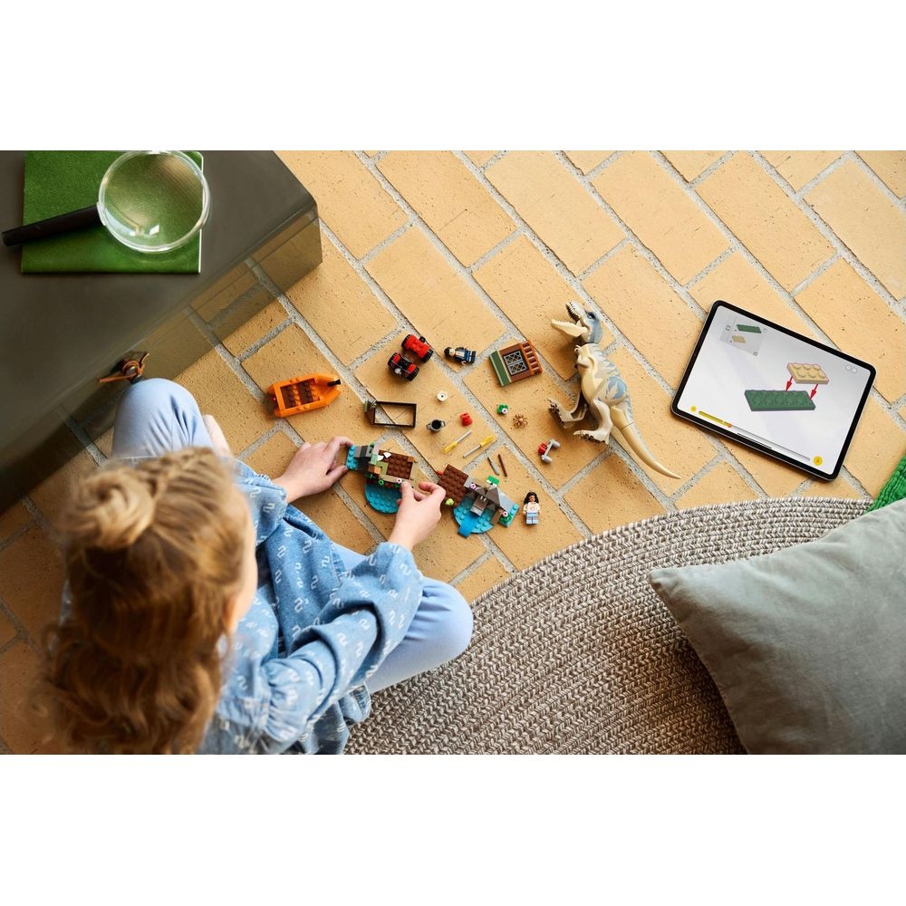 Dziecko buduje dinozaury Lego, korzystając z tabletu jako instrukcji.