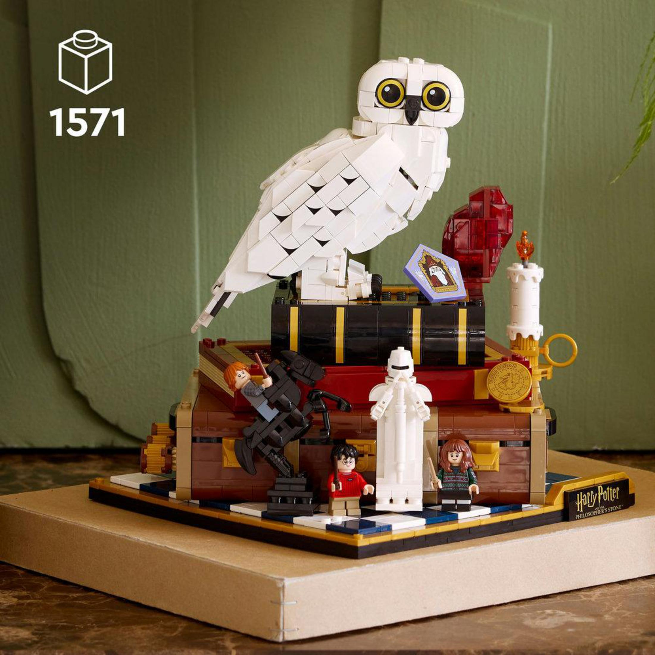 Model Lego z białą sową na książkach, figurkami i świecą.