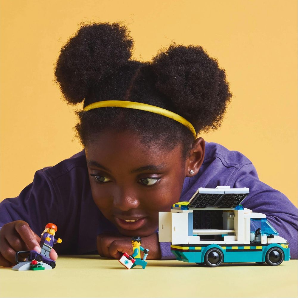 Dziewczynka bawi się figurkami Lego i białym vanem w kolorze turkusowym.