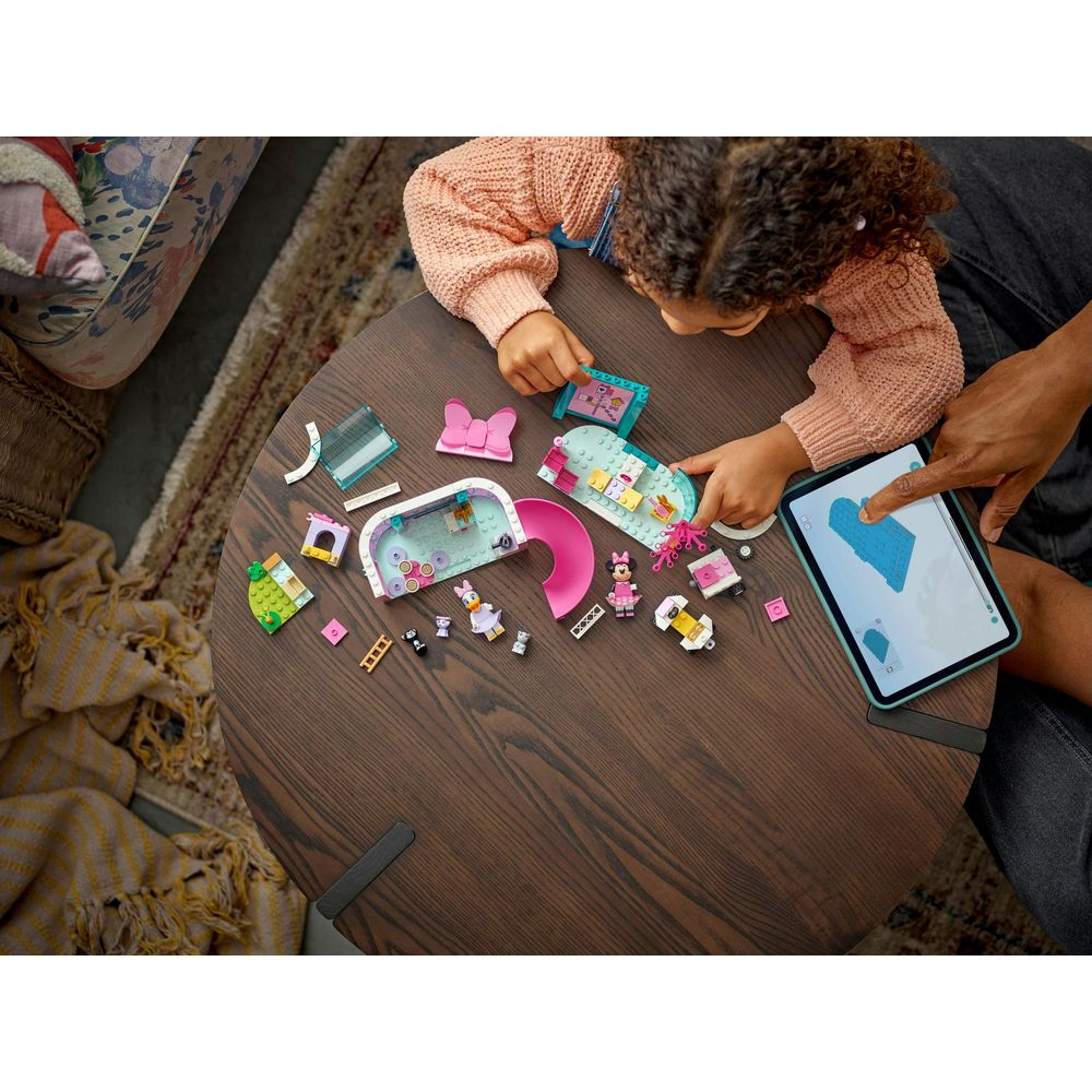 Dziecko buduje zestaw Lego na stole, kierując się instrukcjami na tablecie.