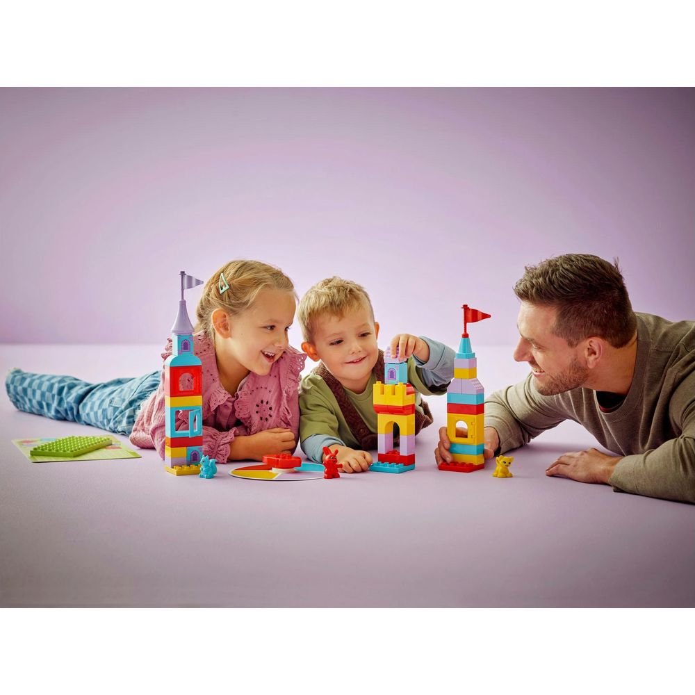 Ojciec i dzieci budują wieże z kolorowych klocków na fioletowym tle.