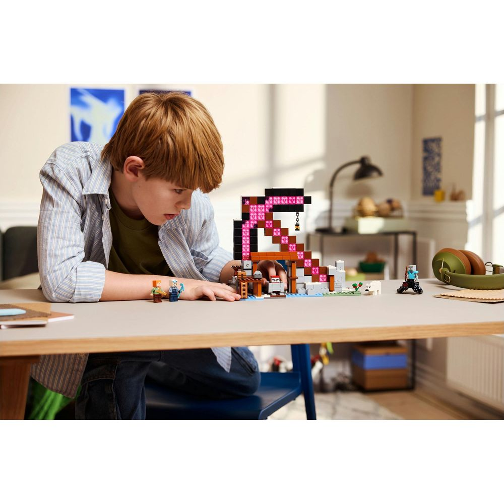 Chłopiec buduje zestaw LEGO Minecraft z różowymi kryształami, TNT i postaciami.