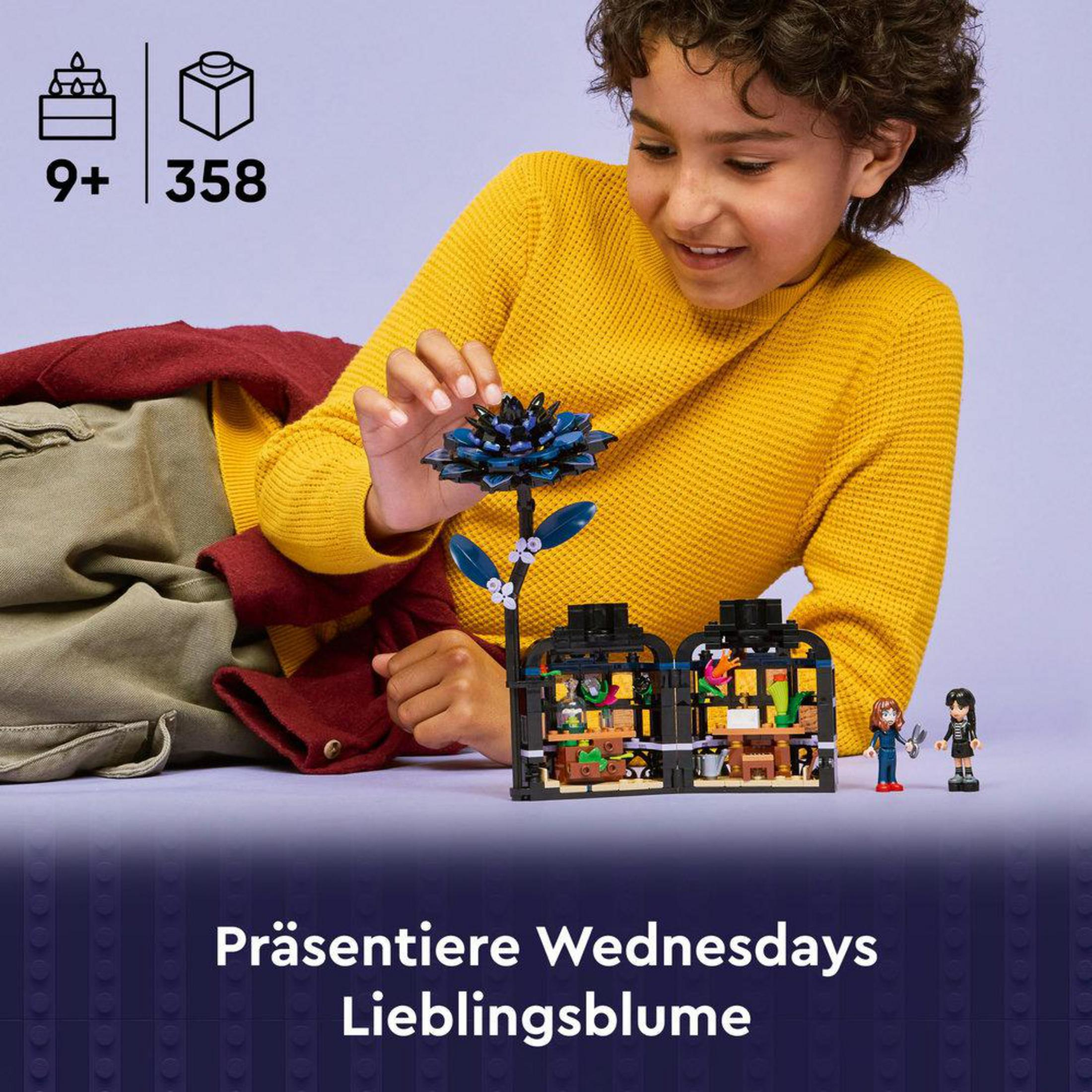 Chłopiec w żółtym swetrze buduje kwiat LEGO i mały domek z figurkami.