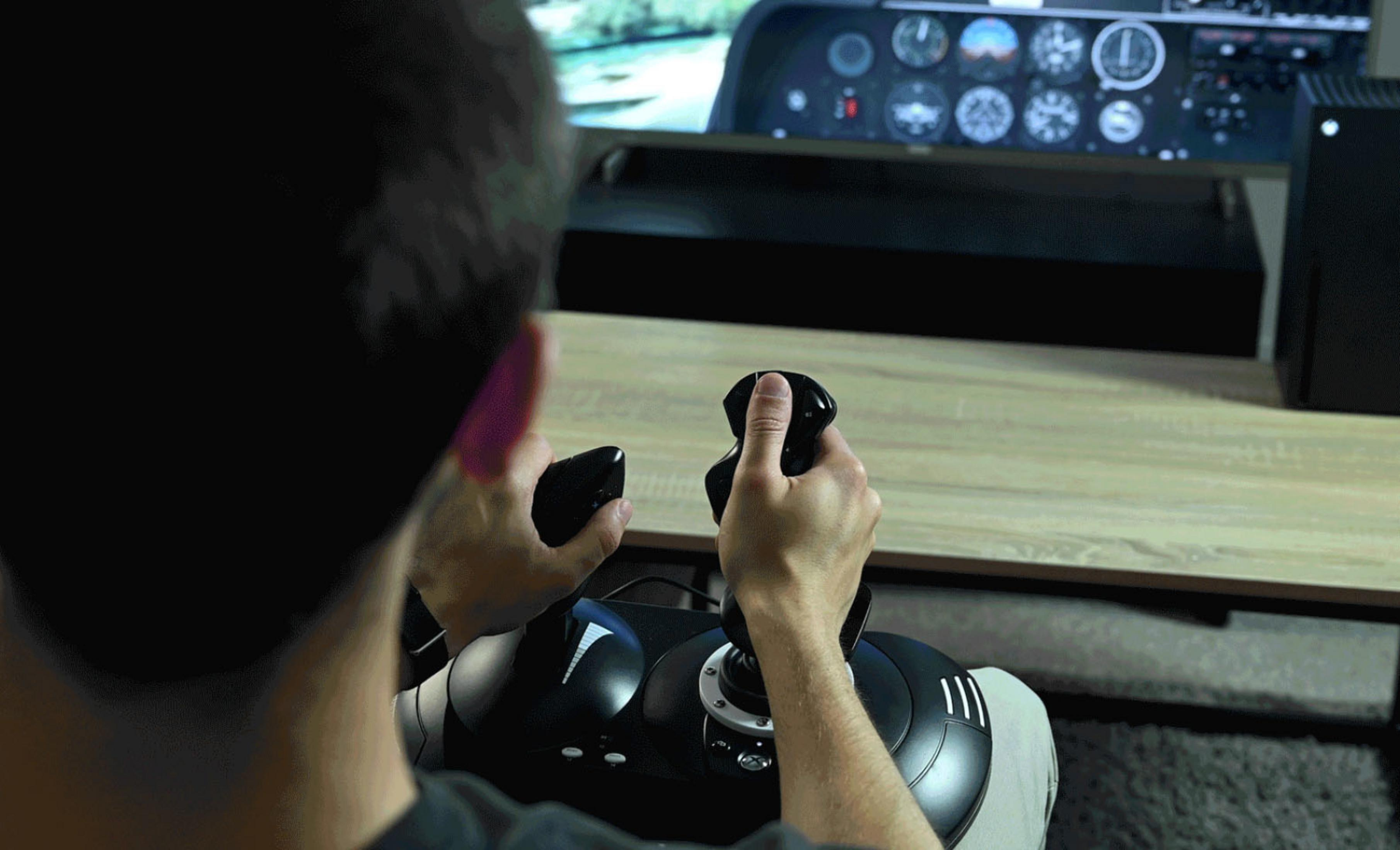 Osoba gra w symulator lotu z joystickiem, patrząc na ekran.