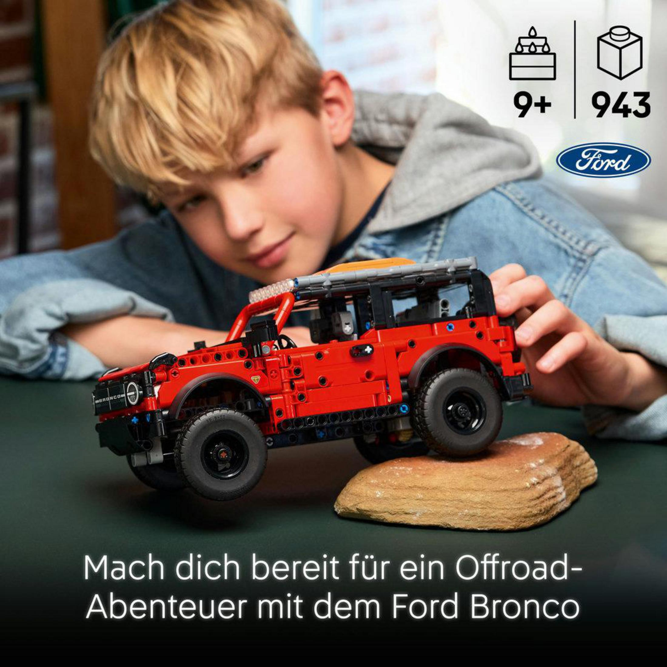 Chłopiec buduje czerwonego Forda Bronco z Lego. Zestaw dla osób 9+ lat, zawiera 943 elementy.