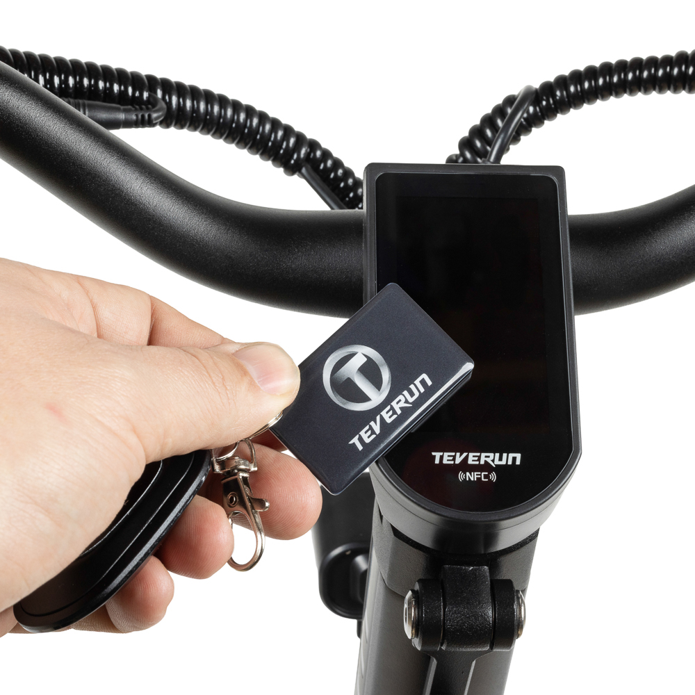 Ein Schlüsselanhänger mit TEVERUN-Logo wird vor einem E-Scooter-Display gehalten.