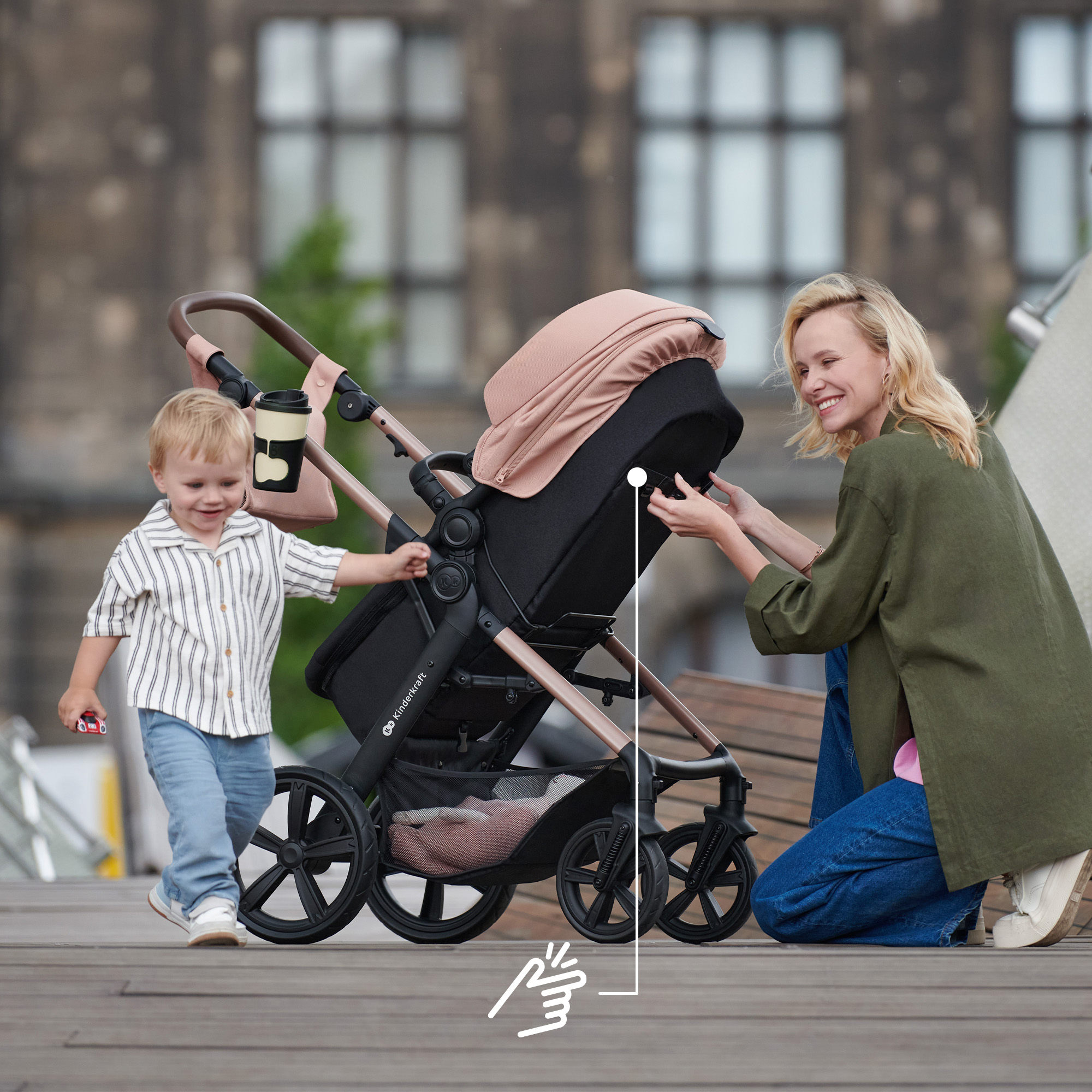 Eine Frau kniet neben einem Kinderwagen, während ein Kleinkind daneben steht.