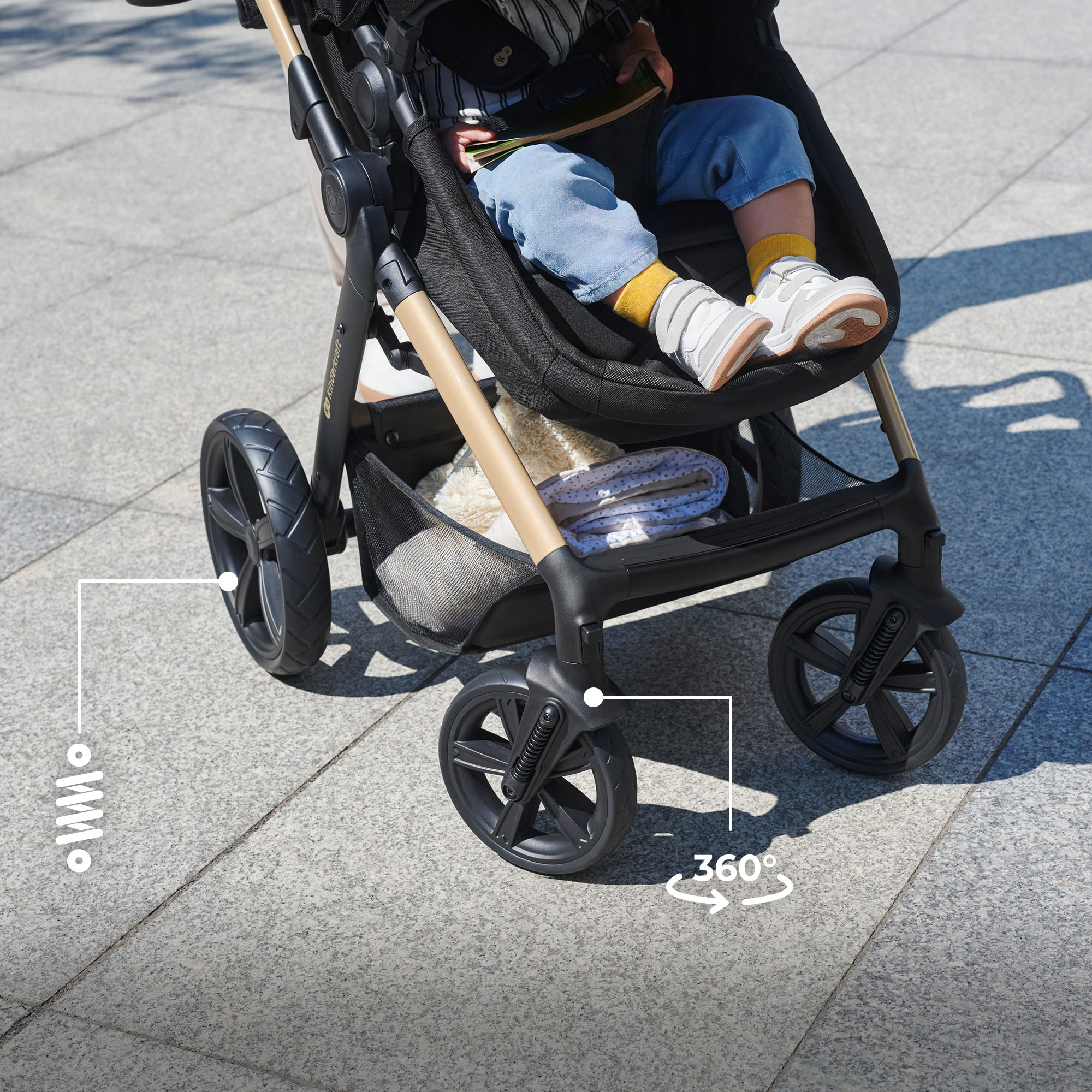 Ein Kind sitzt in einem Kinderwagen mit Federung und 360-Grad-Rädern.