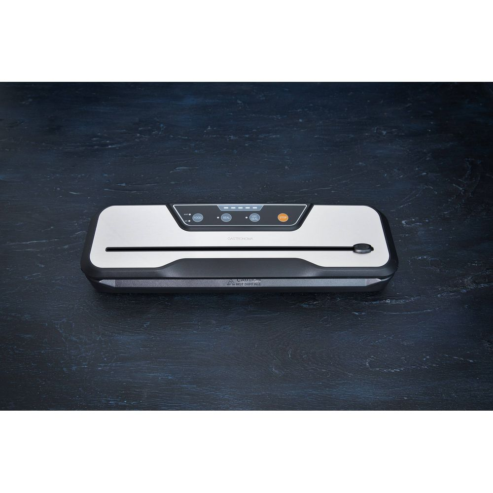 Srebrna zgrzewarka próżniowa z czarnymi detalami na ciemnym drewnianym stole.