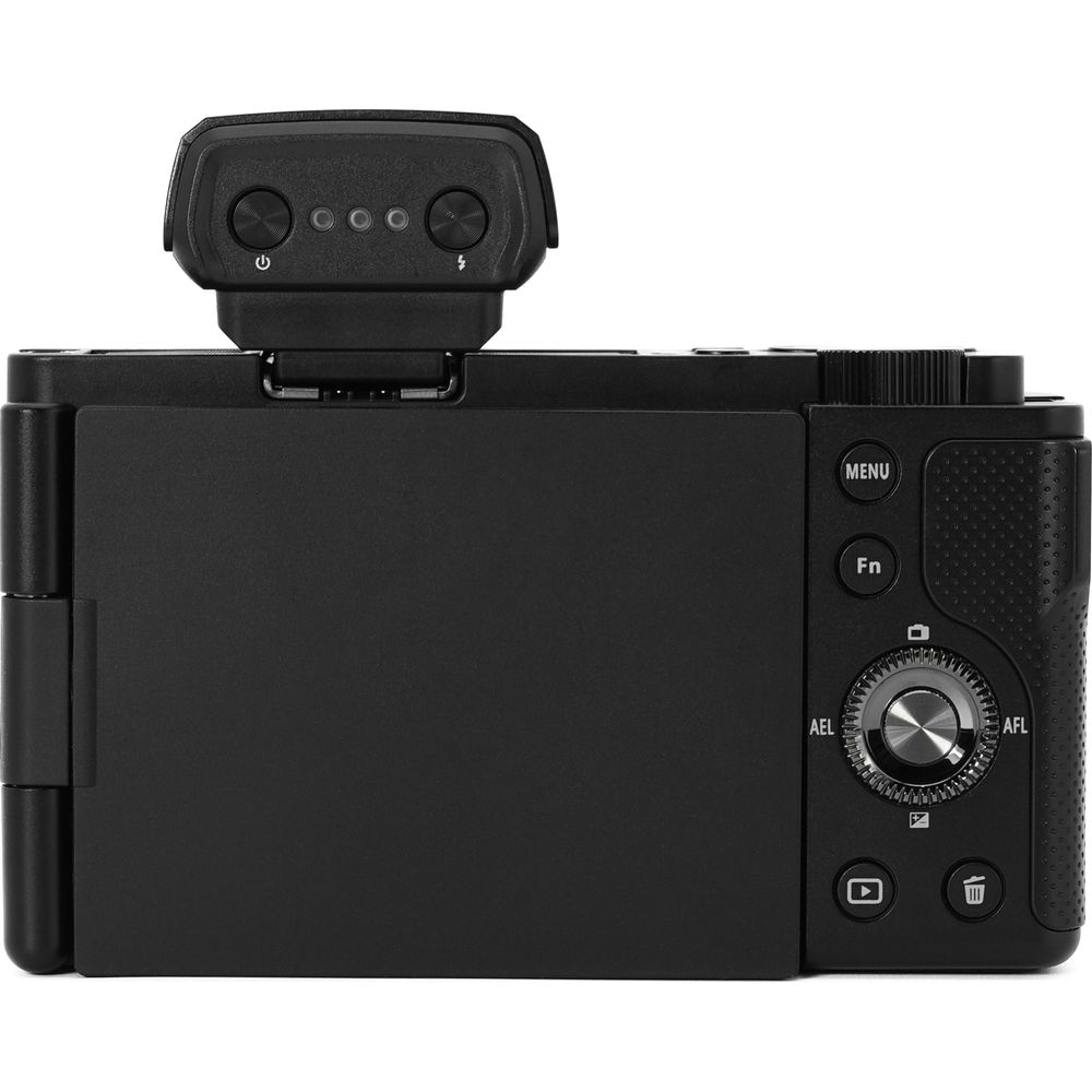 Tył czarnego aparatu cyfrowego z odchylonym ekranem i sankami na lampę.