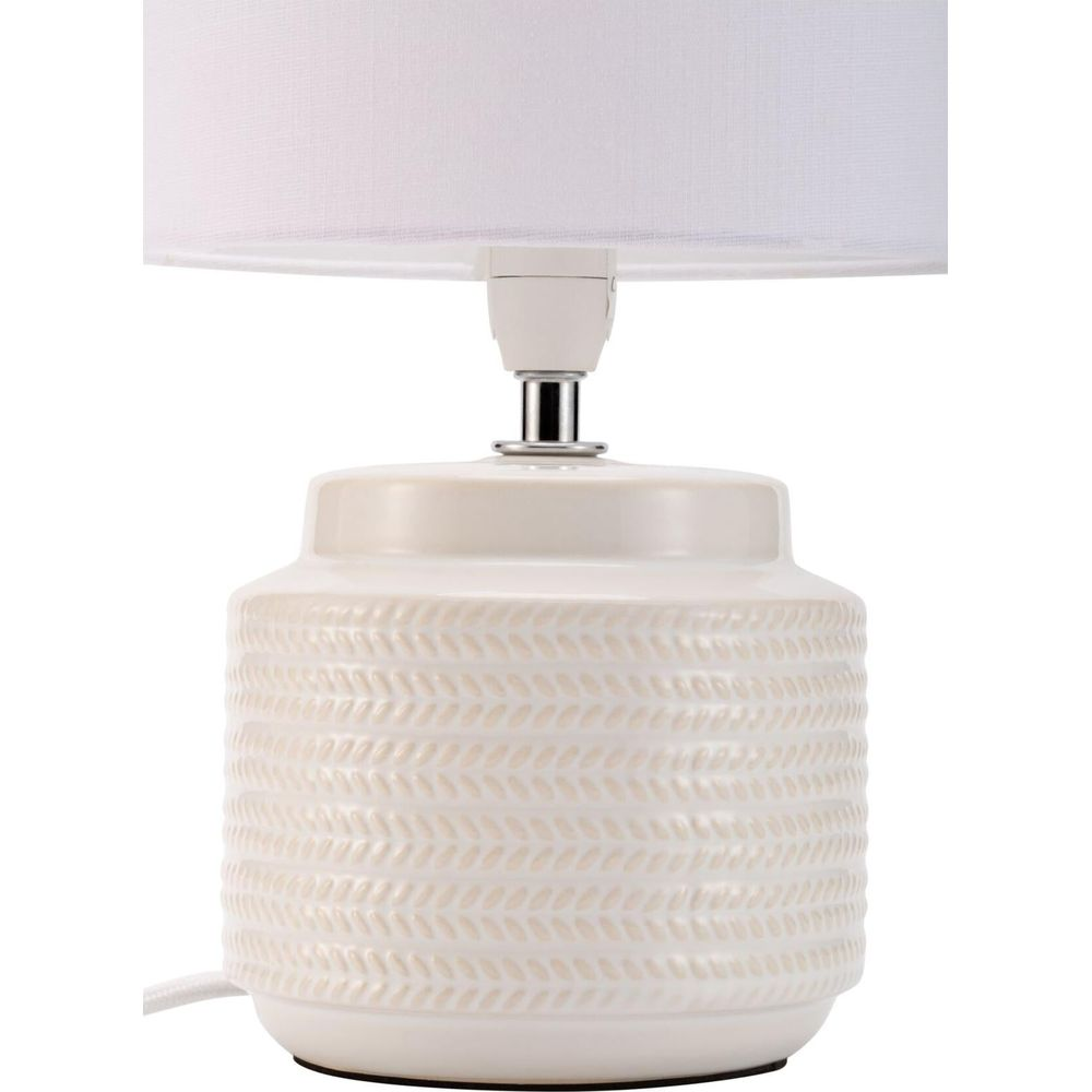 Kremowa ceramiczna lampa z białym kloszem i wzorem liści.