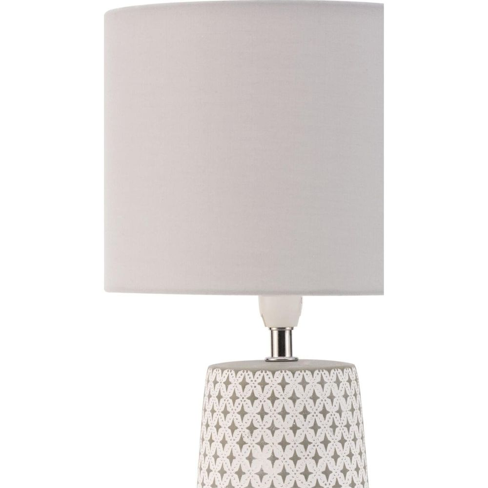 Szara lampa z białym abażurem i geometrycznym wzorem.
