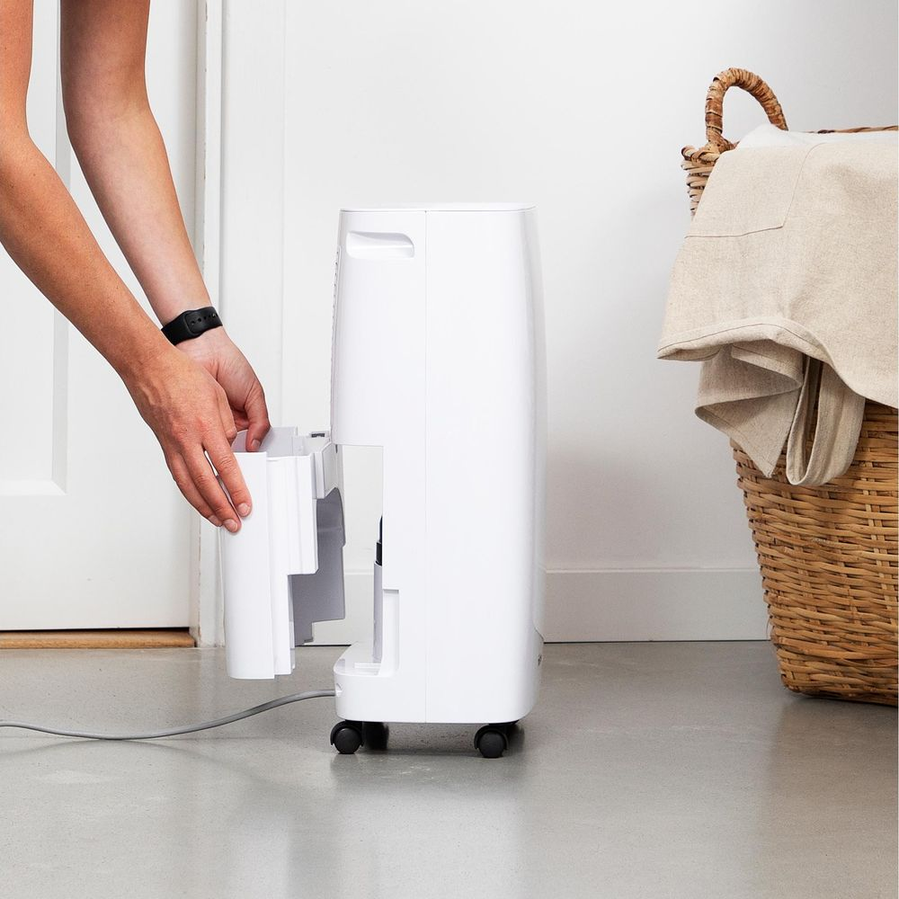 Osoba wyciąga biały pojemnik z białego osuszacza powietrza.
