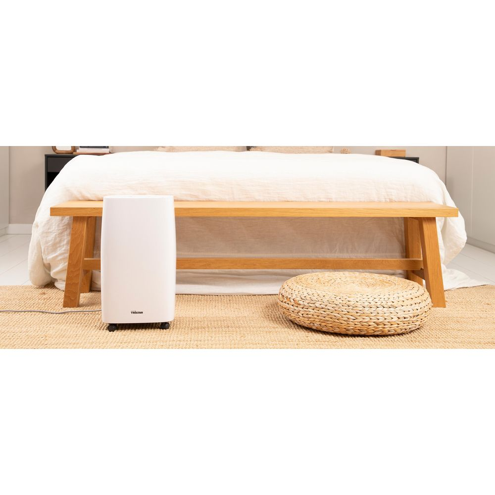 Biały osuszacz powietrza obok okrągłego kosza na drewnianej ławce.