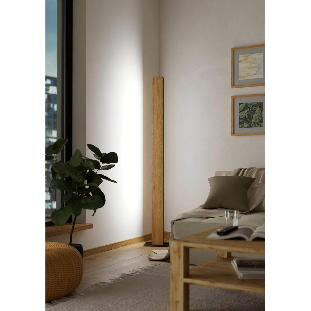 Ein heller Wohnraum mit einem Holzboden, einer Pflanze, einem Sofa und einem Tisch.