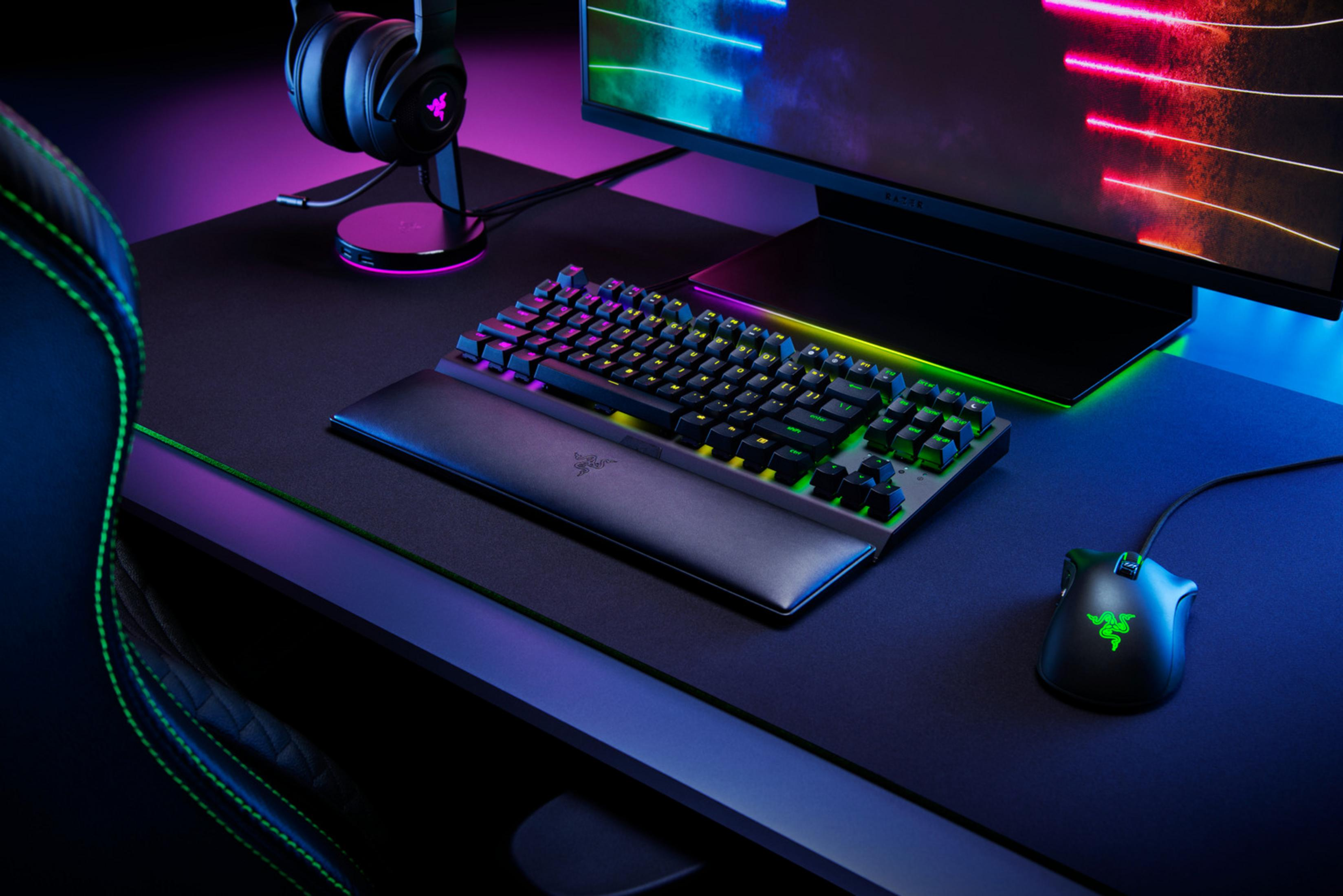 Un setup de jeu Razer avec clavier, souris, casque et moniteur dans le noir.