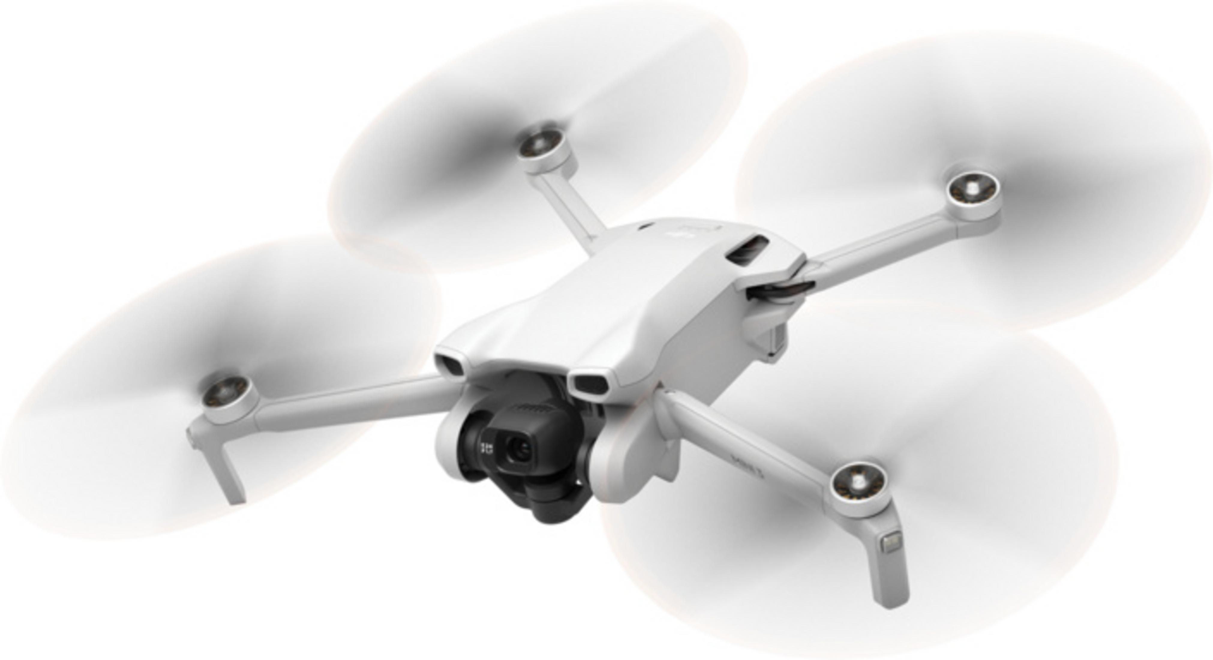 Un dron blanco con cuatro hélices flota en vuelo, con una cámara al frente.