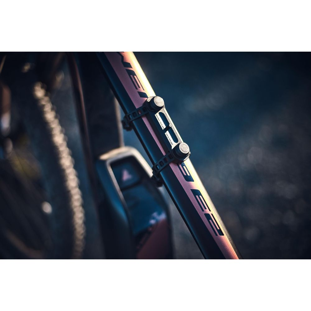 Czarny uchwyt z dwoma śrubami jest przymocowany do ramy roweru.