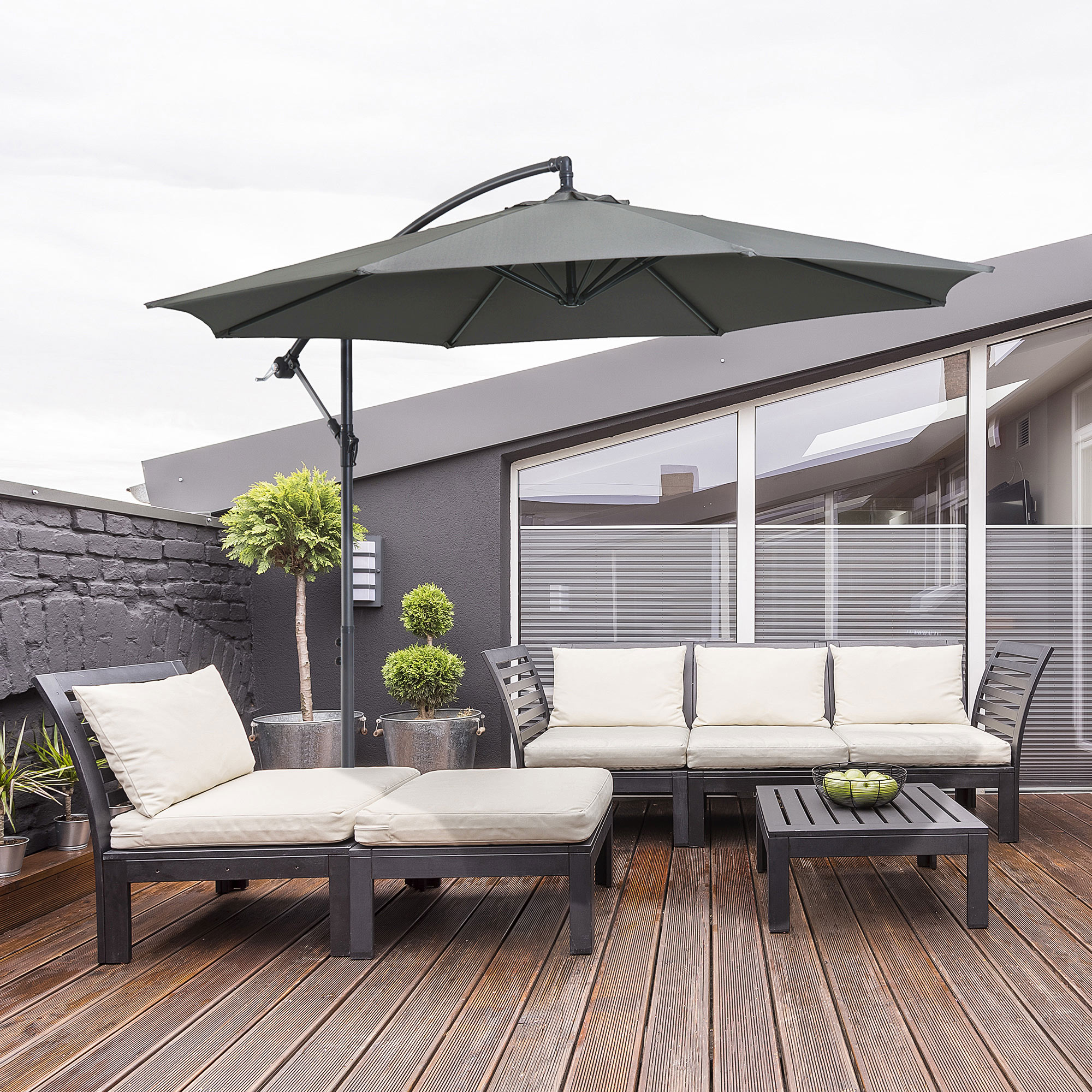 Muebles de exterior en una terraza de madera bajo una sombrilla.