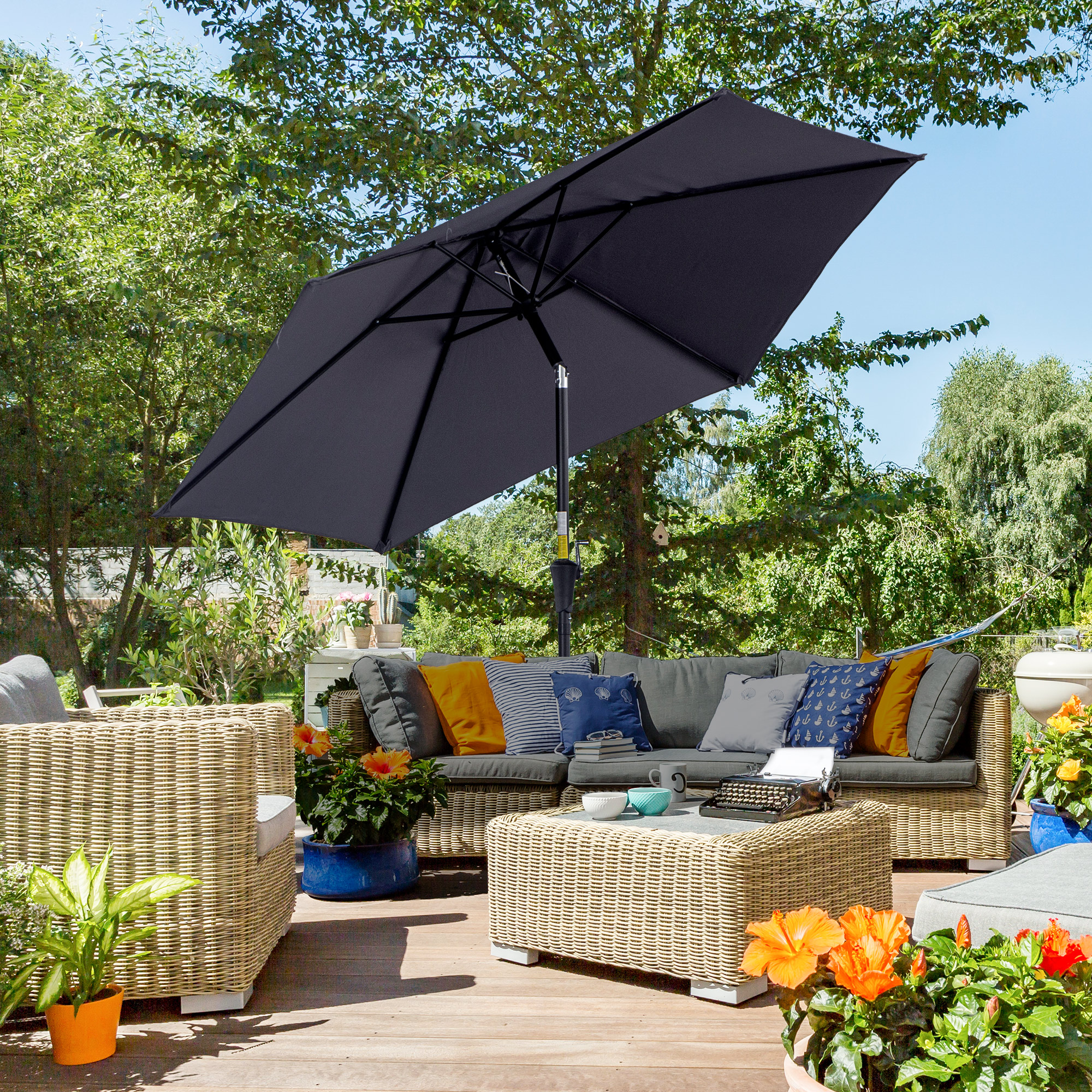 Un set di mobili da giardino con divano, tavolino, sedie e ombrellone.