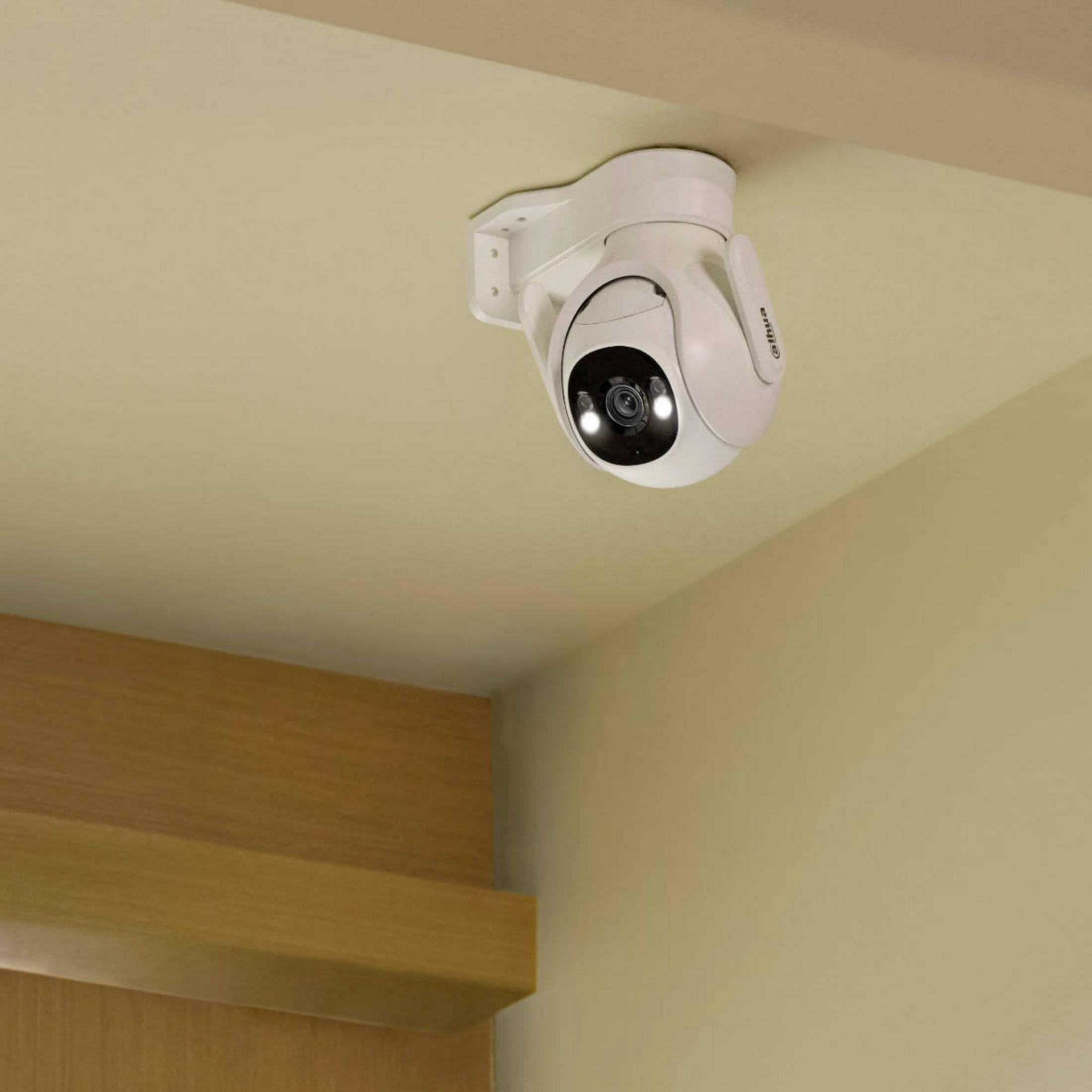 Caméra de sécurité blanche montée au plafond, avec objectif et lumières visibles.