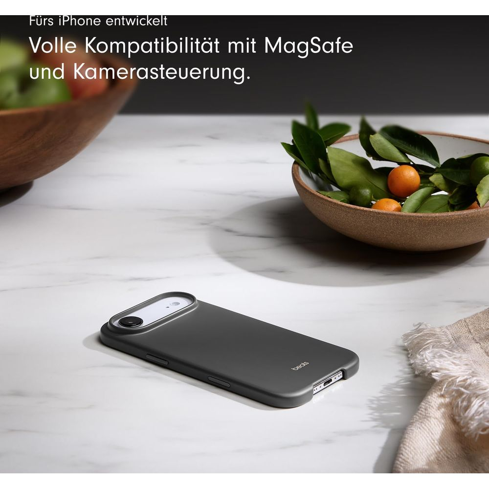 Funda gris oscura para iPhone sobre mármol junto a un cuenco con naranjas.