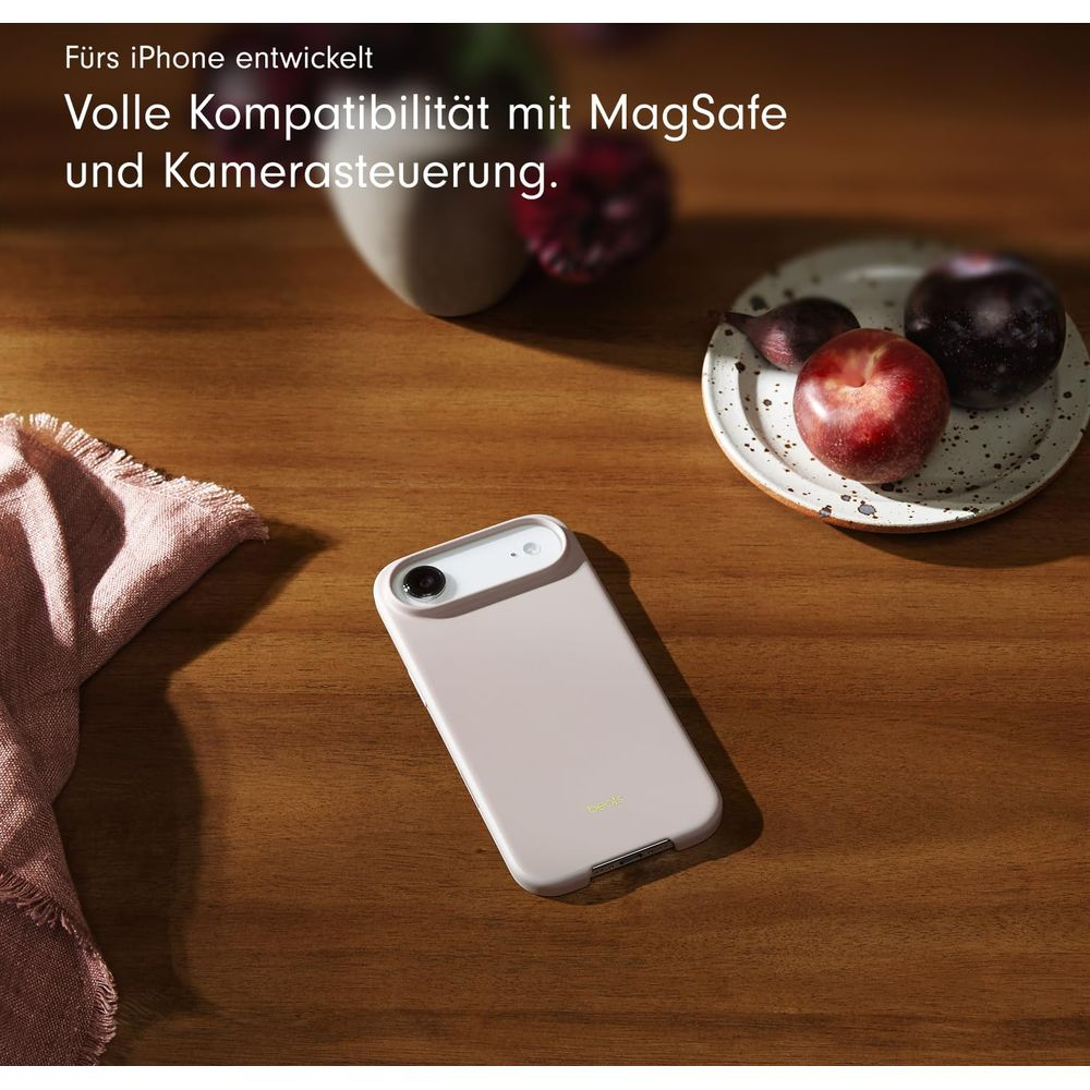 Jasnoróżowe etui na iPhone leży na drewnianym stole obok serwetki i owoców.