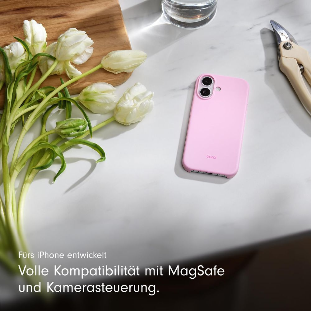 Ein rosafarbener Handyhülle liegt neben weißen Tulpen und einer Schere.