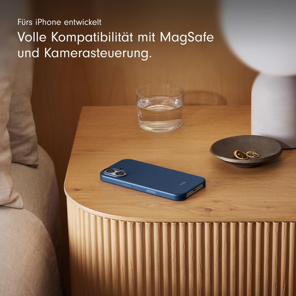 Niebieskie etui na telefon leży na drewnianym stole obok szklanki wody.