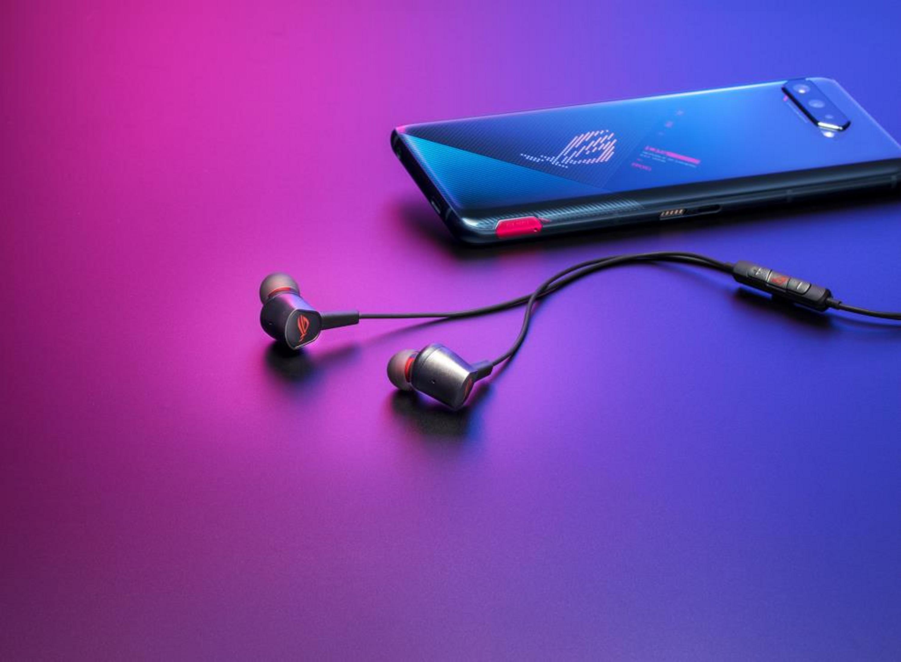 Smartfon i słuchawki douszne na tle fioletowo-różowym.