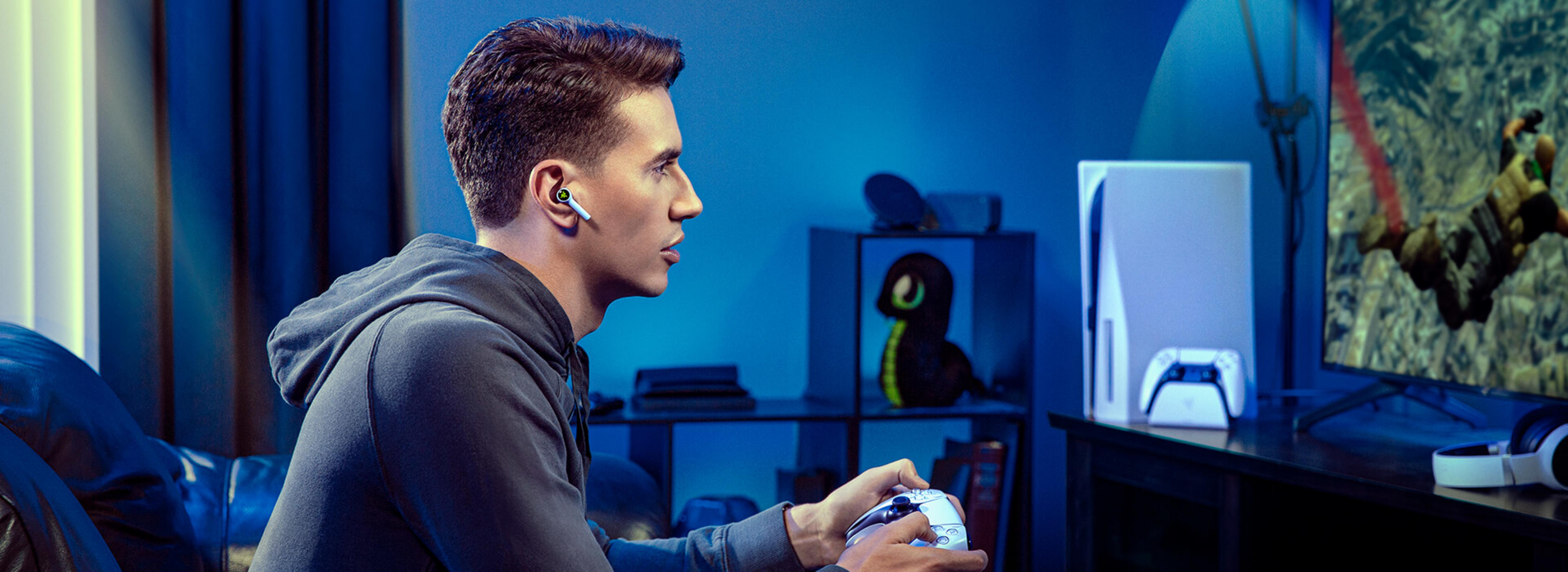 Een man speelt videogames met oordopjes en een controller.